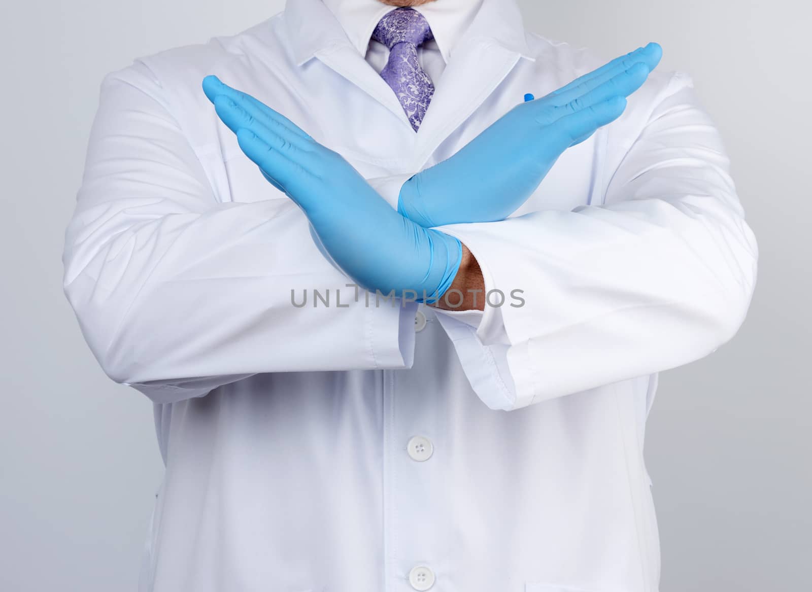 doctor man in a white coat and blue latex gloves crossed his arms in front of his chest, gesture of rejection, denial