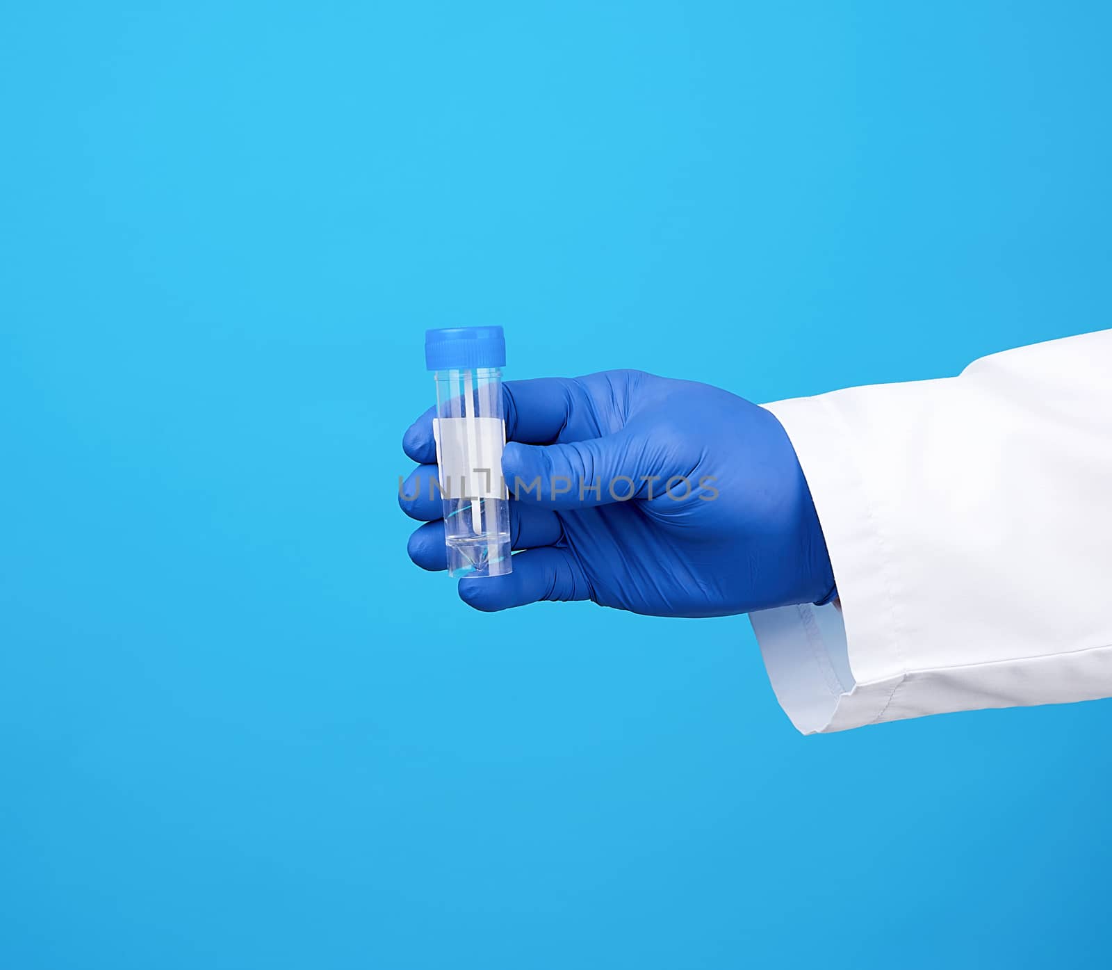 doctor in a white coat and blue sterile latex gloves holds a plastic jar for stool analysis, blue background