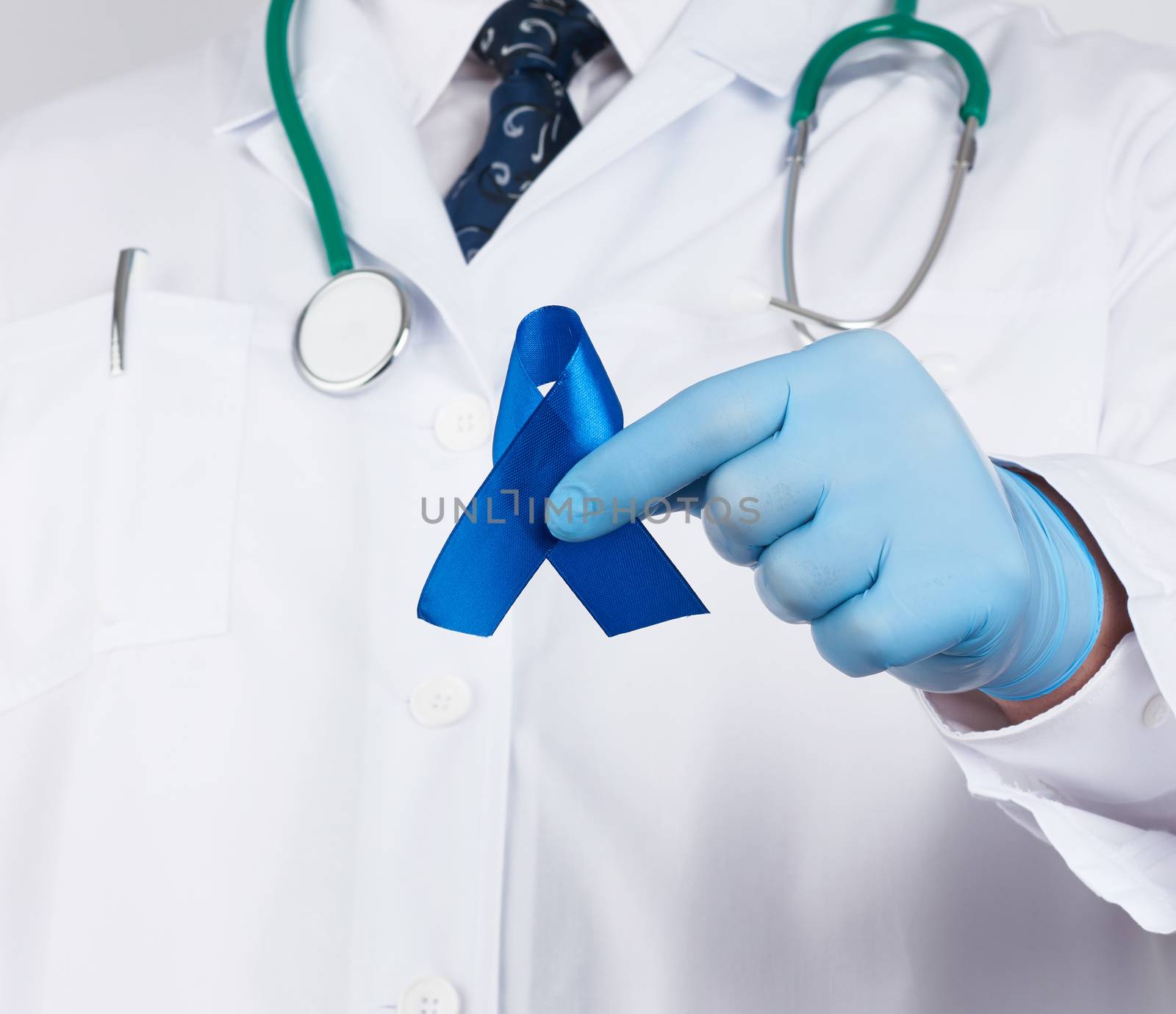 doctor in white uniform and sterile latex gloves holds a dark blue ribbon, concept of timely research and disease prevention colon malignancies, chronic fatigue syndrome, tuberous sclerosis