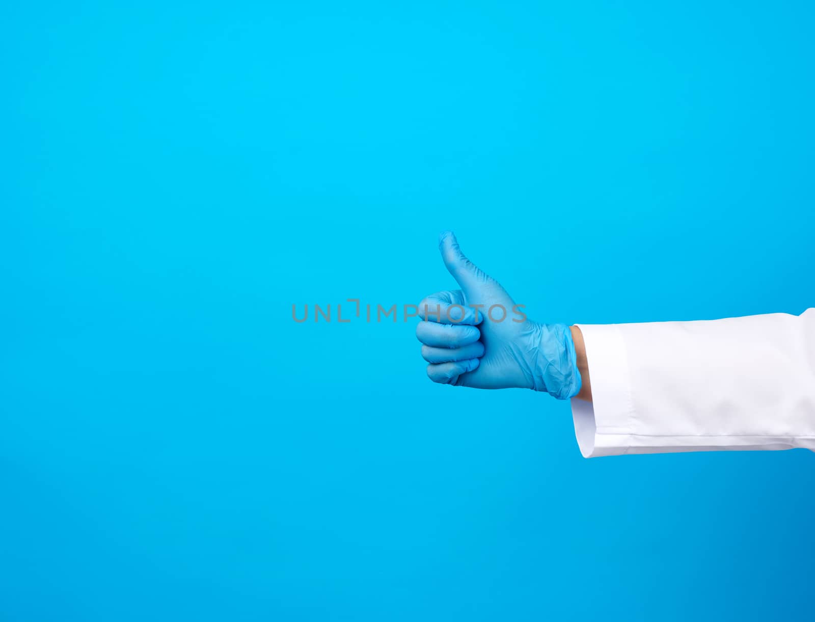 doctor in a white coat shows with his hand a gesture like, wearing blue latex medical gloves, close upm copy space