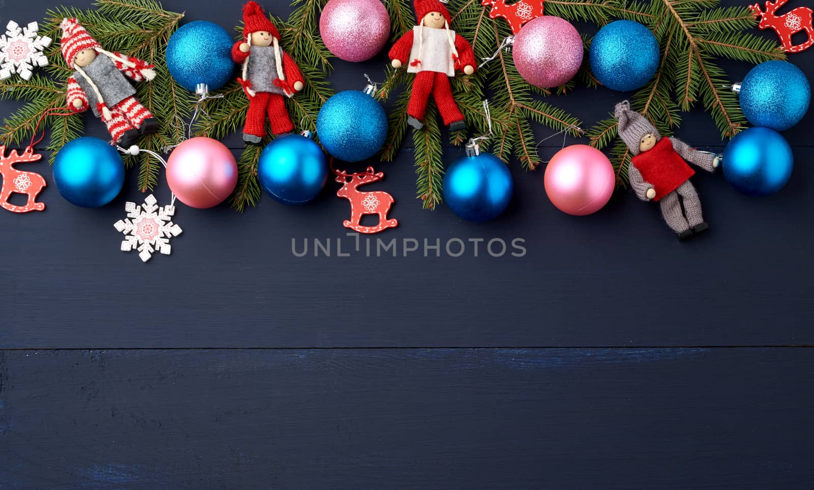 green spruce branches, Christmas blue and pink balls, carved wooden decor on a blue wooden background from boards, copy space