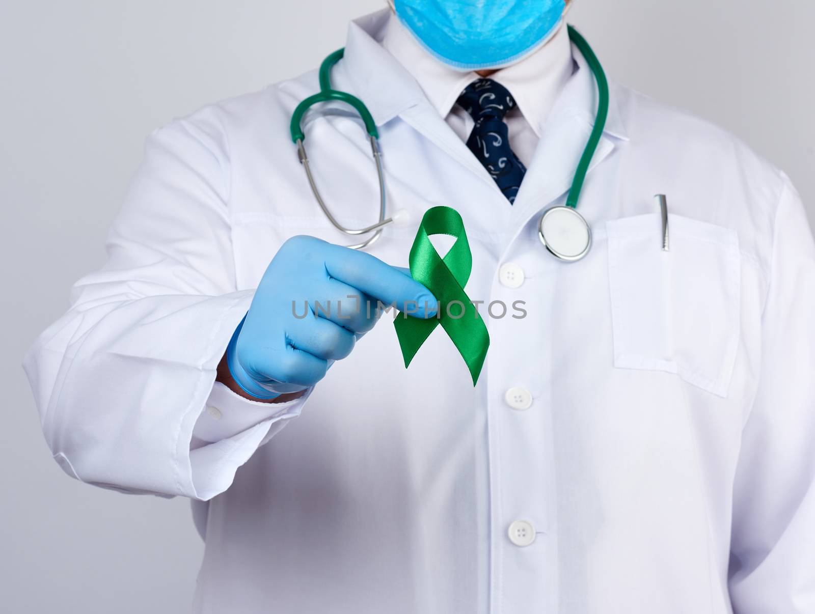 doctor in white uniform and latex gloves holds a green ribbon as a symbol of early research and disease control, symbol of Lyme disease, kidney transplantation and organ donation