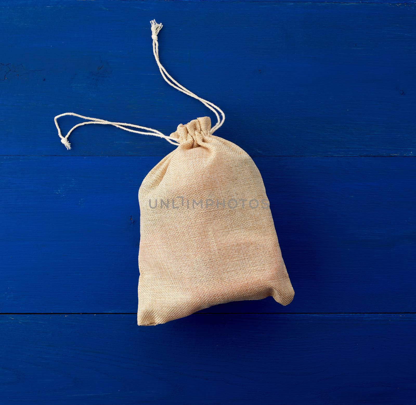 small full brown canvas bag with ties, blue wooden background, top view. Reusable eco bag. 