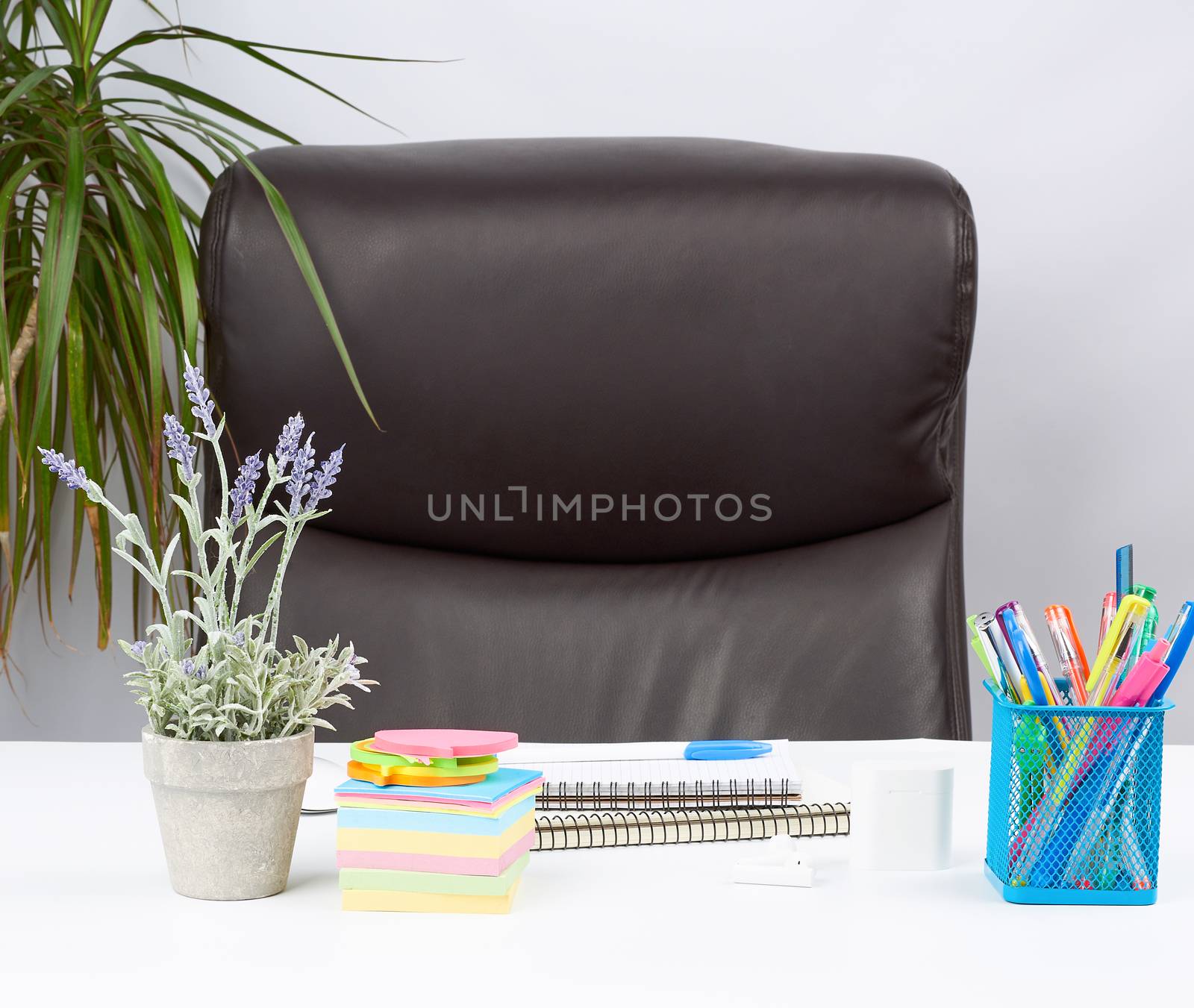 empty brown armchair and white desk with stationery, workplace