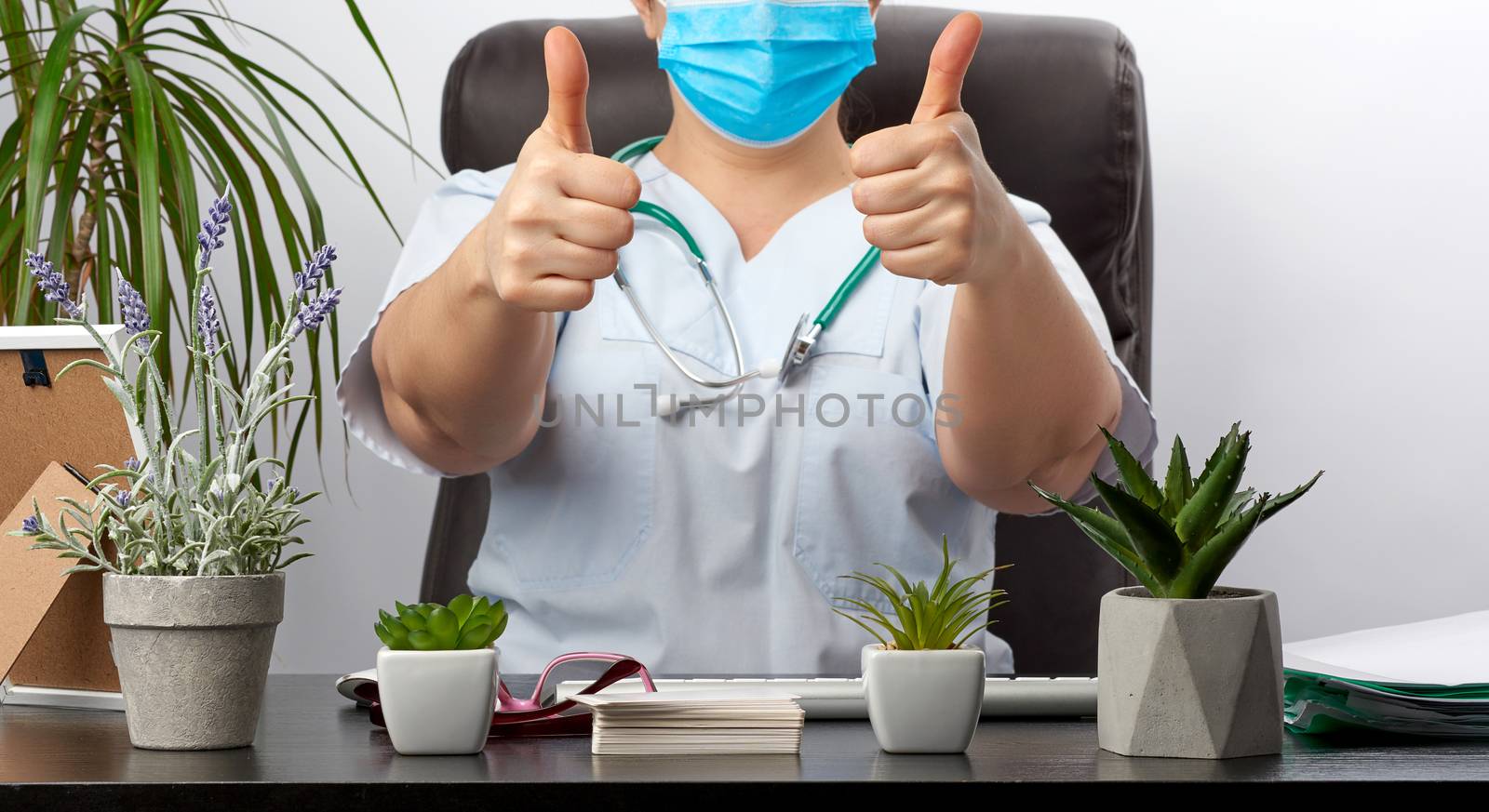 medic woman in white uniform showing like gesture in hand, approval concept, close up, therapist sits at a black table in the office