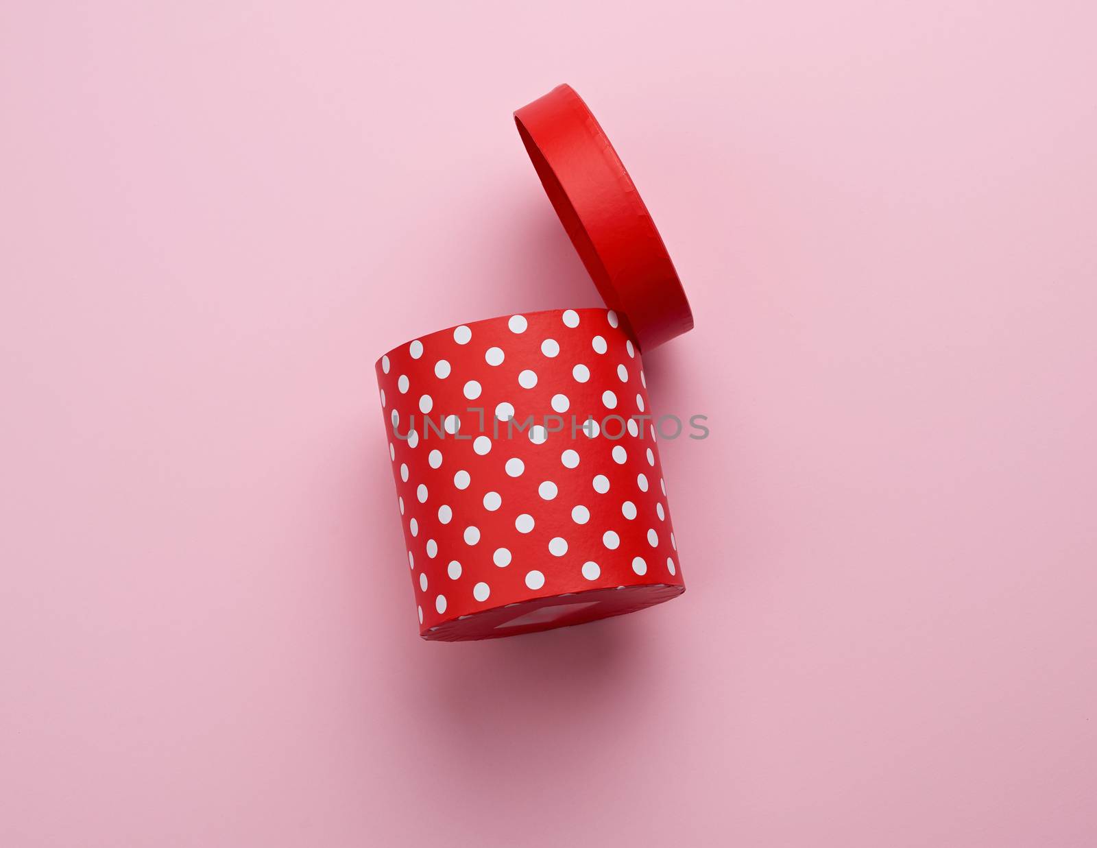 empty round red cardboard box in white polka dots on a pink background, holiday backdrop