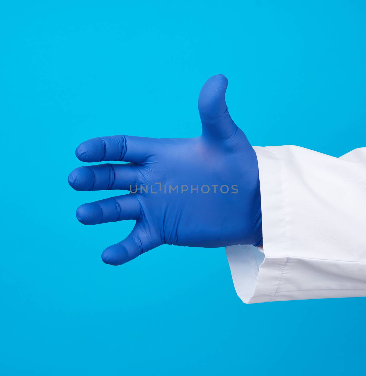 doctor’s hand is wearing a blue sterile rubber glove holding an object, blue background, element for a designer