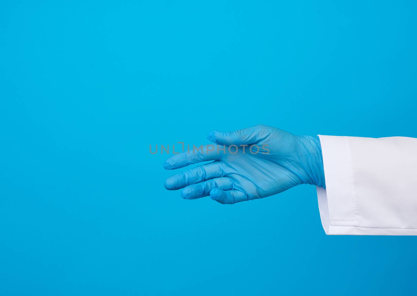 medic in a white coat, blue latex gloves pulls his hand for a handshake on a blue background