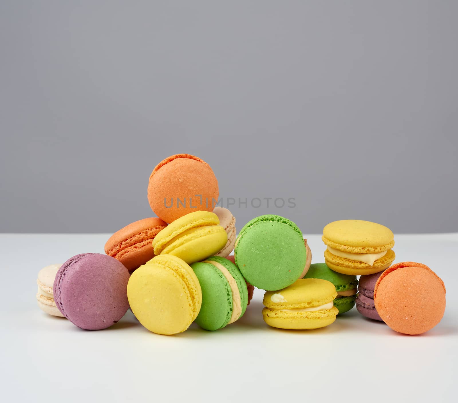 round baked multi-colored almond flour cakes macarons on a white background, close up