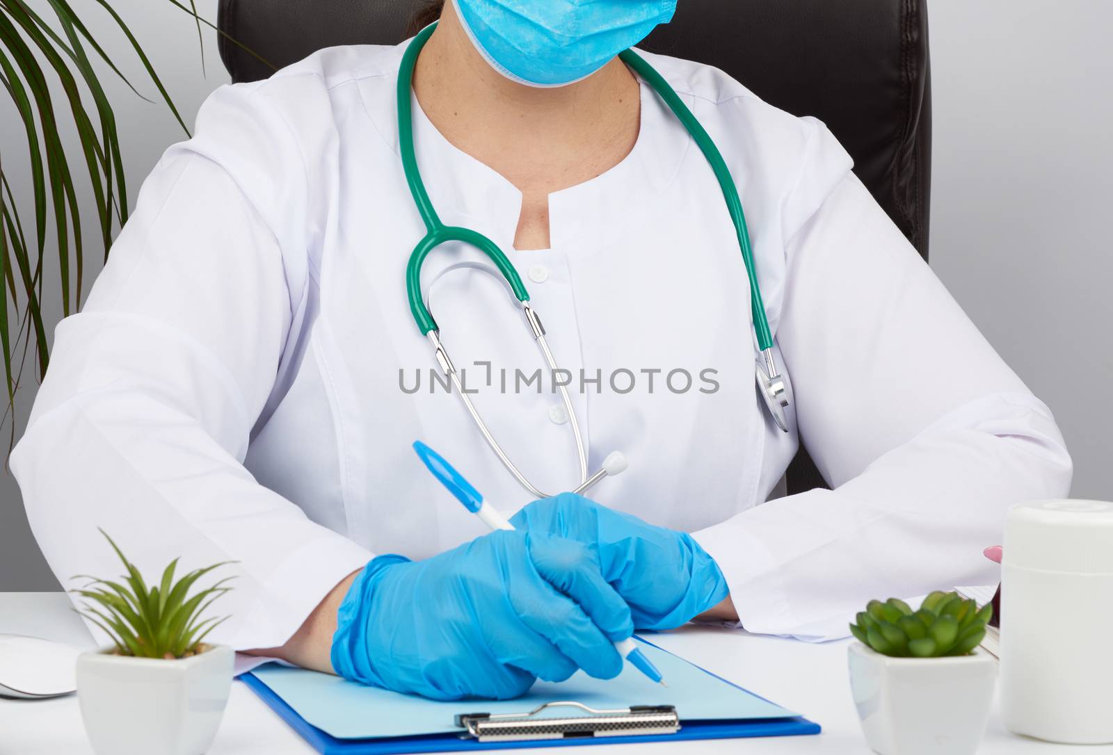 woman doctor in a white coat, sterile medical gloves writes a prescription on a form, therapist sits on a chair at a white table, workplace
