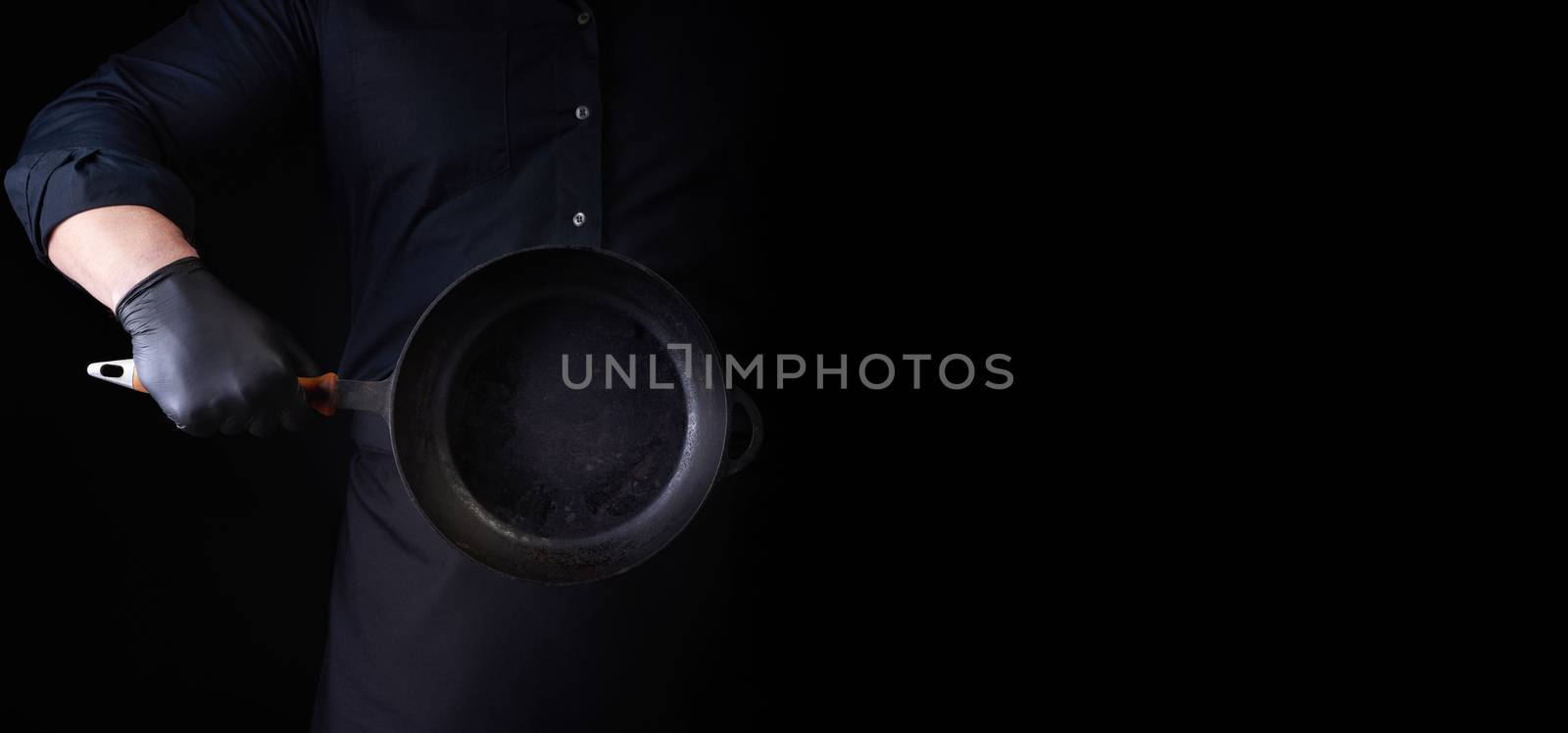 male cook in black uniform and latex gloves holds an empty round by ndanko