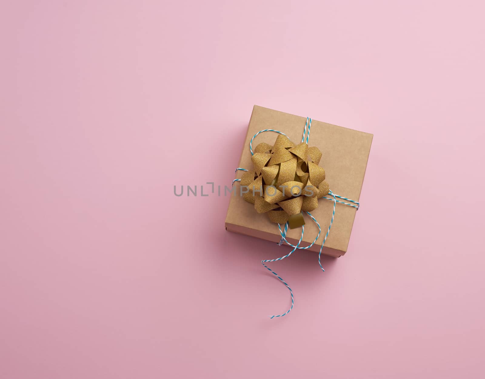 closed brown square box with a gift tied rope on a pink background, top view, empty place for an inscription