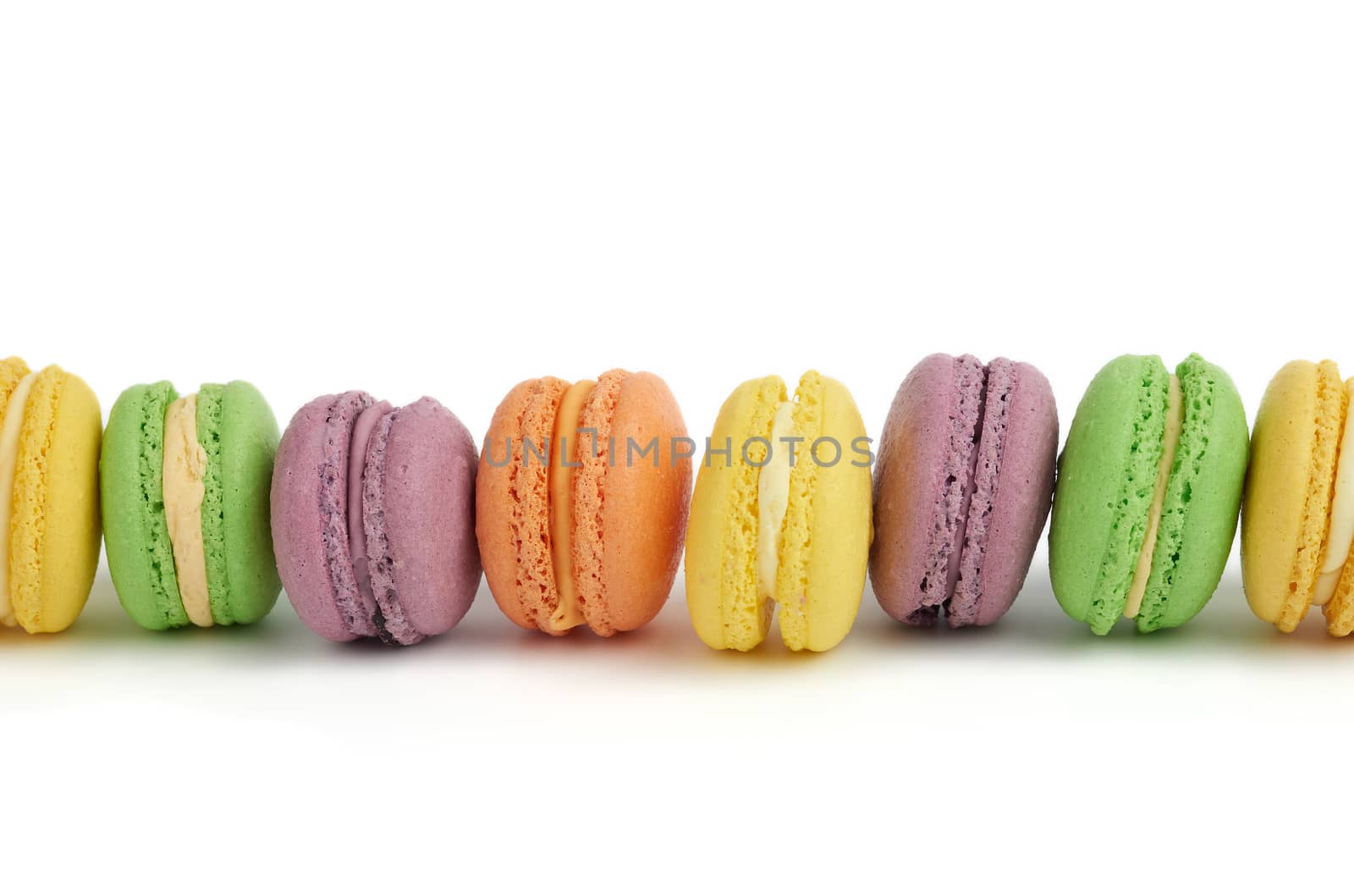 multicolored round baked macaroon cakes isolated on a white background, dessert stands in a row
