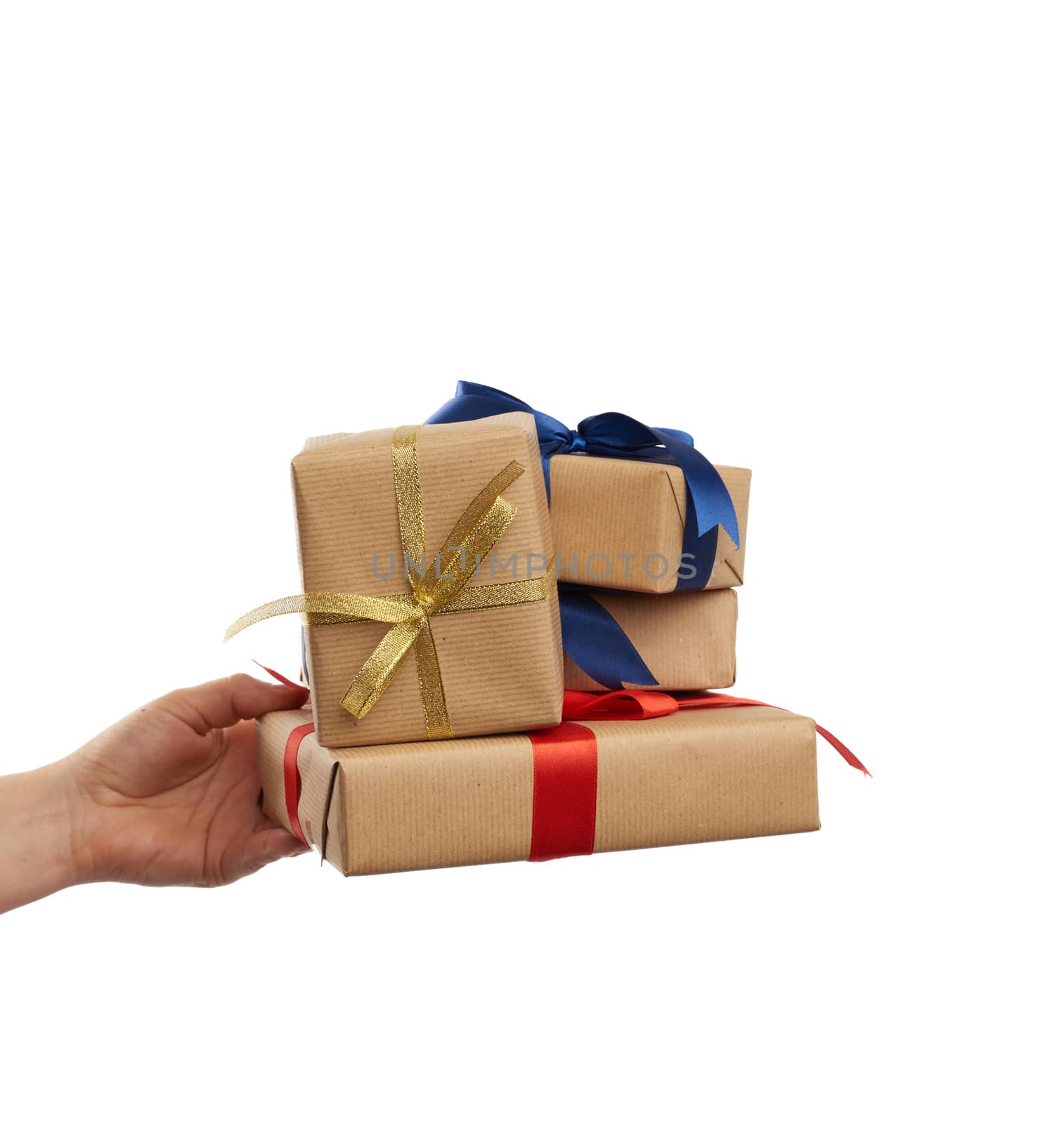 hand holds a stack of wrapped gifts in brown craft paper with tied silk bows, subject is isolated on a white background