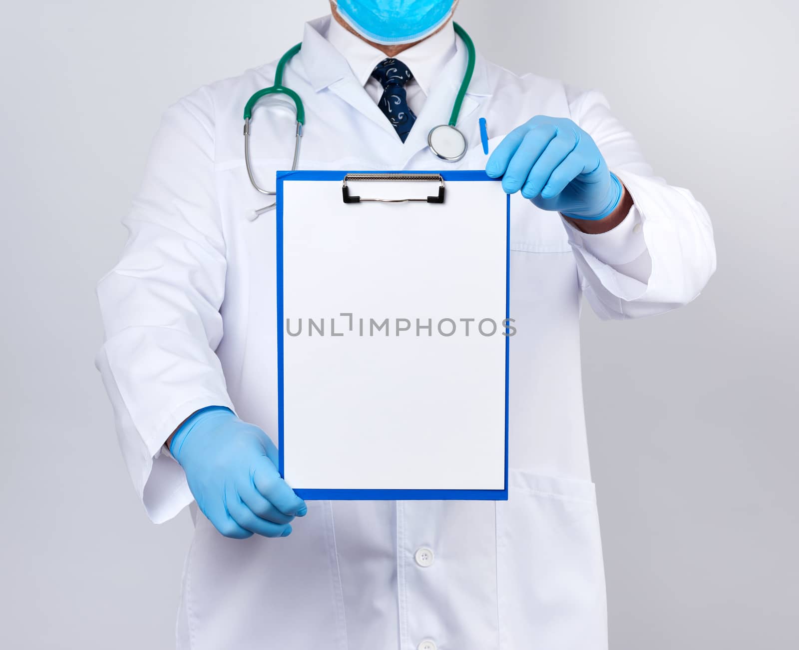 male doctor in a white coat, blue latex gloves, a stethoscope hanging on his neck holding a paper holder with a white blank sheet, place for writing a prescription and text