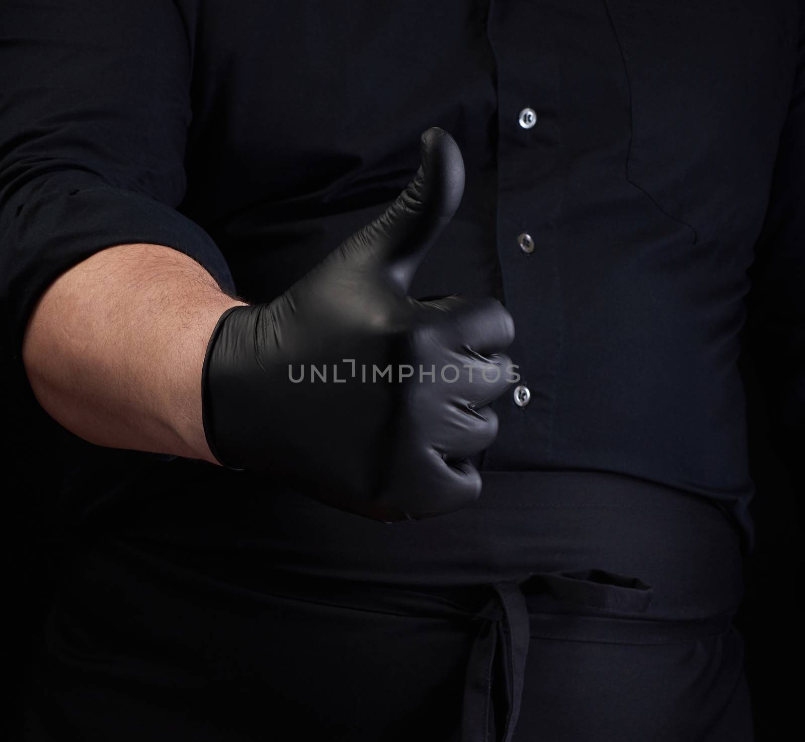 male cook in black uniform and black latex gloves shows like approval gesture, close up