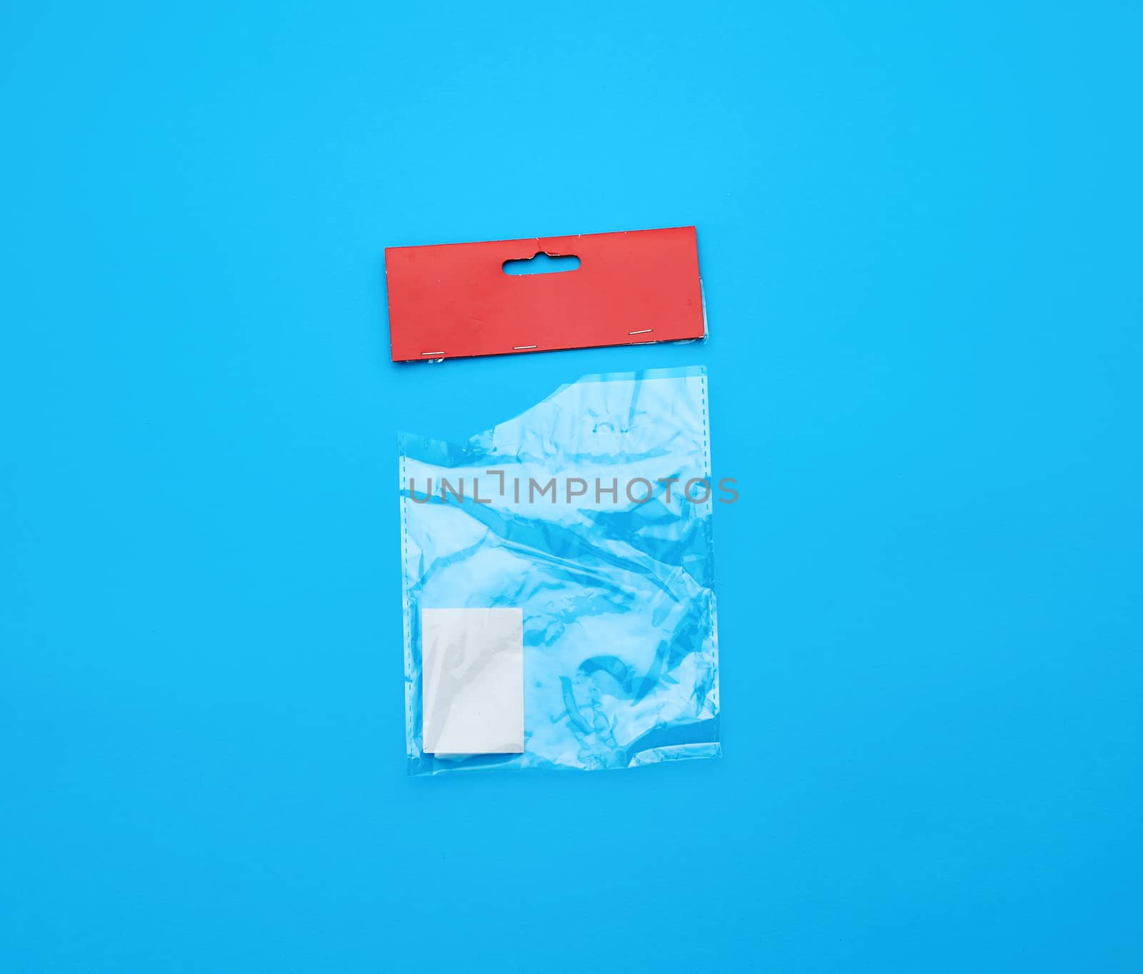 transparent torn plastic bag with paper red top for packaging goods, blue background