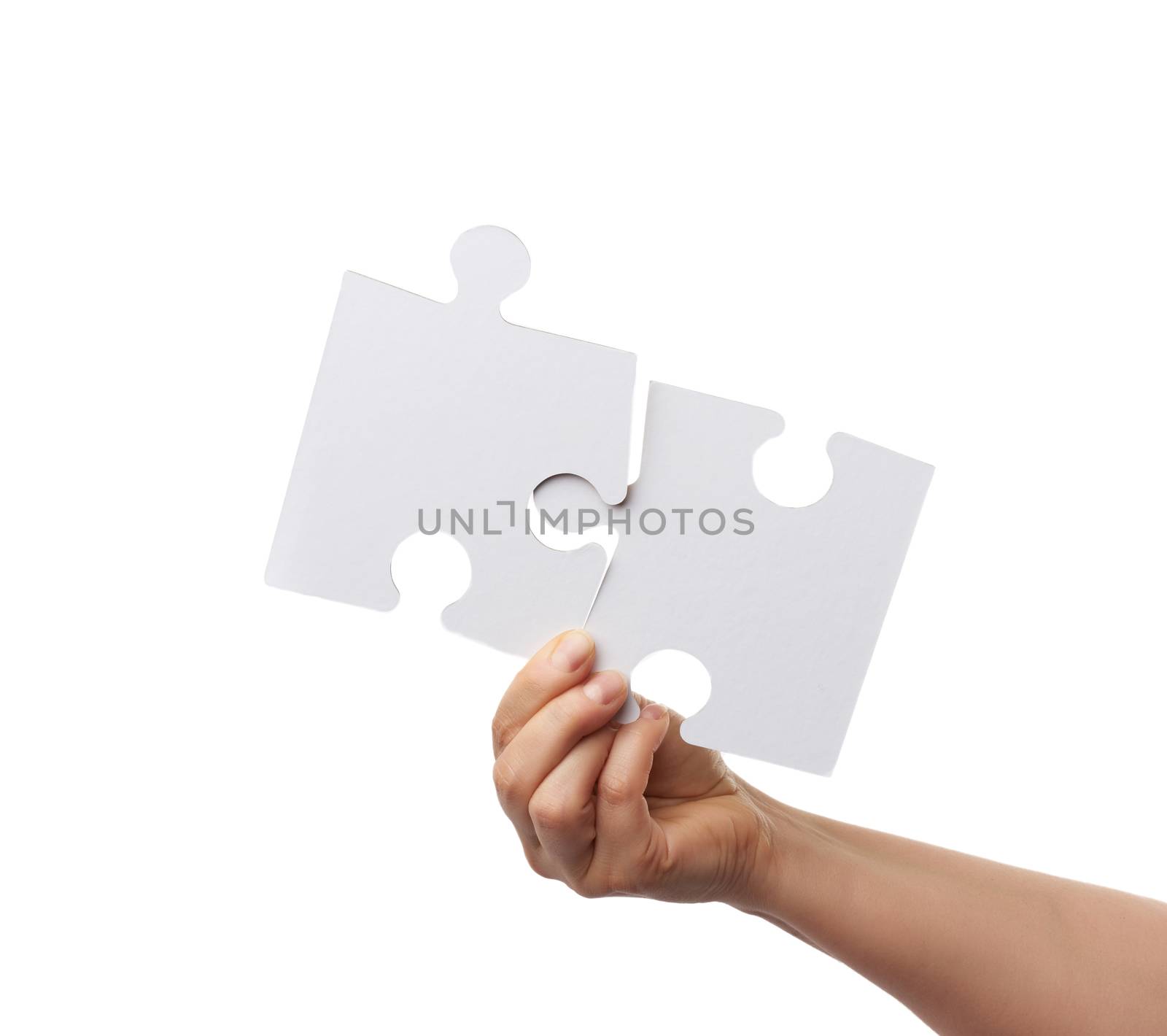 female hand holds two large paper empty white jigsaw puzzles isolated on white background, close up