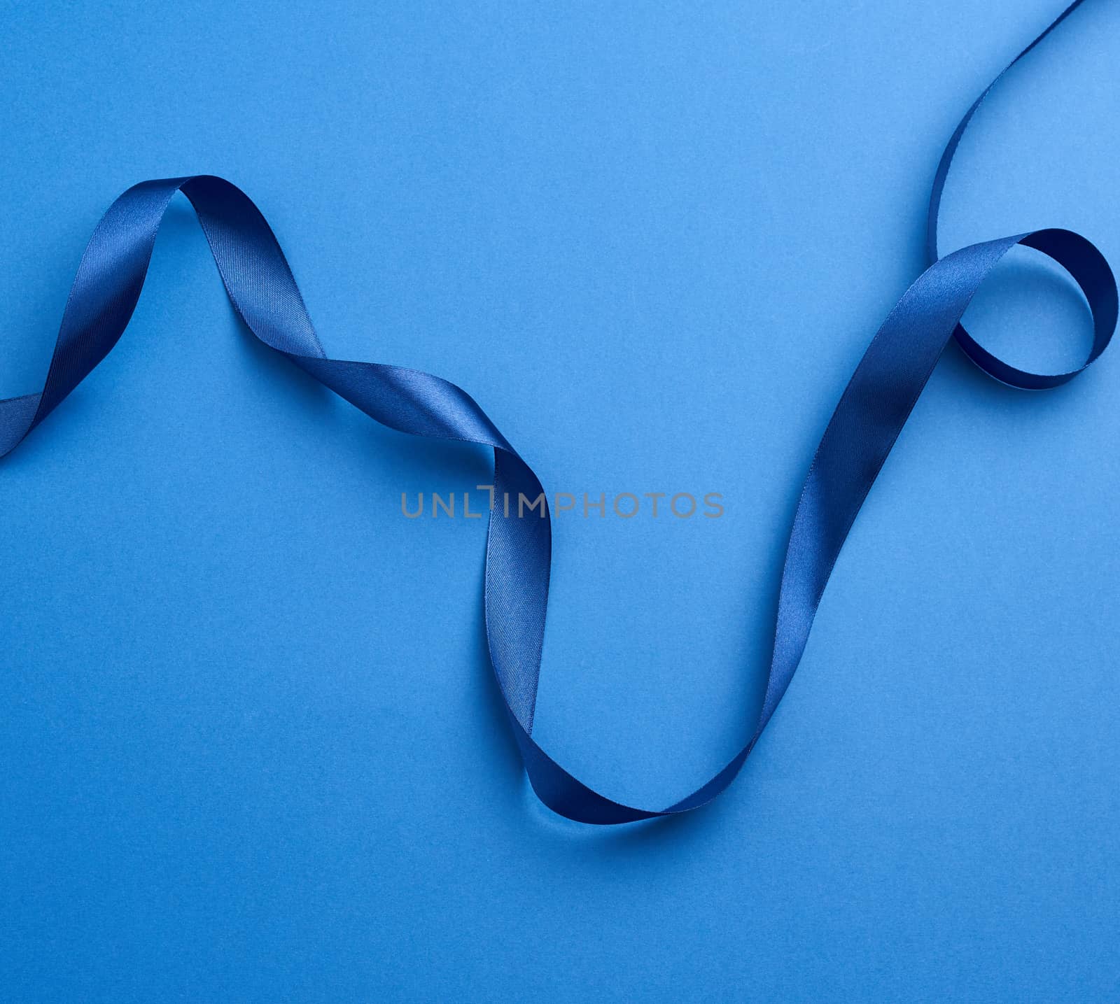 blue silk thin ribbon twisted on a blue background, trendy classic color, close up