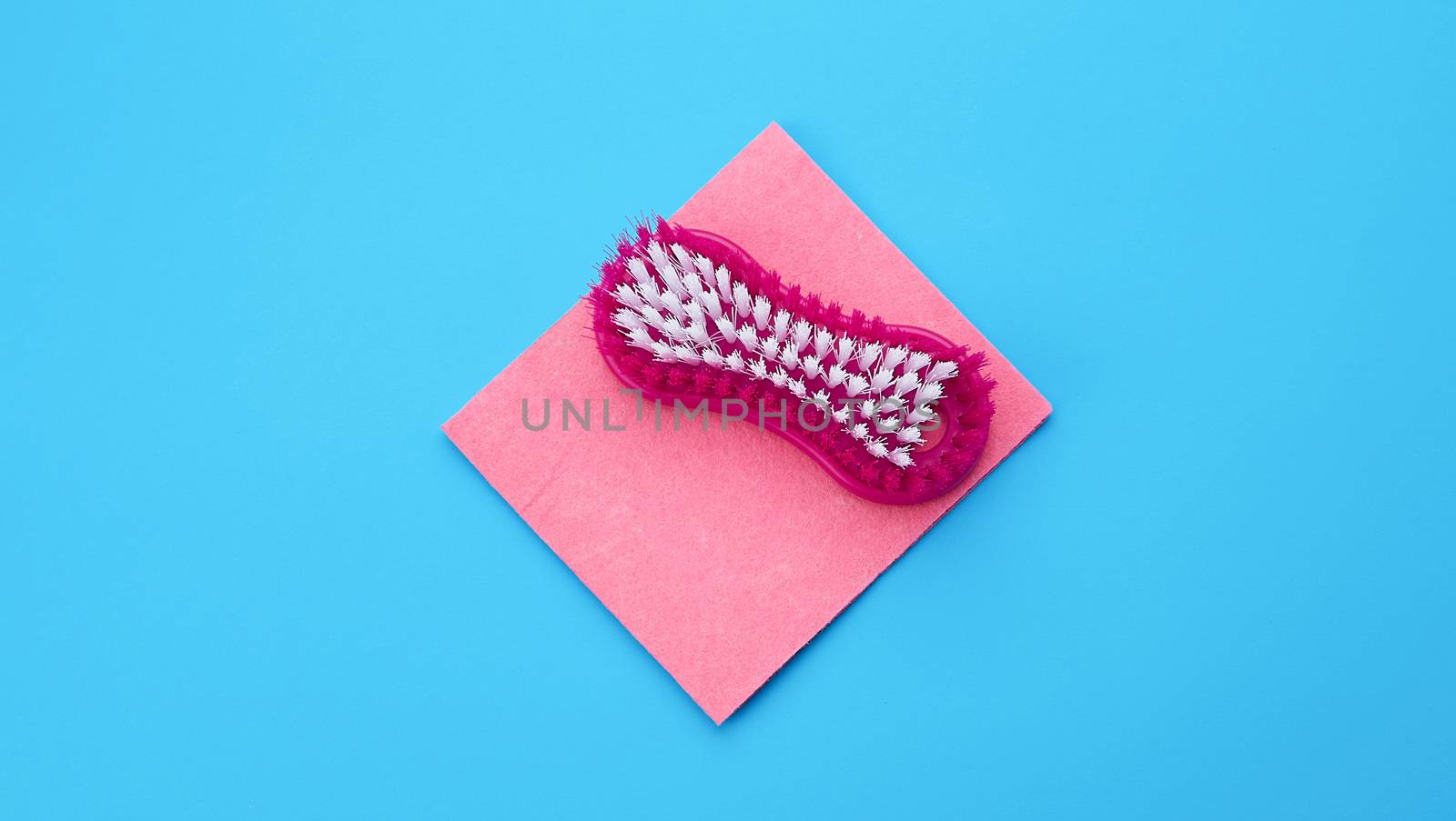 plastic pink brush and square dishwashing sponges on a blue background, top view, flat lay