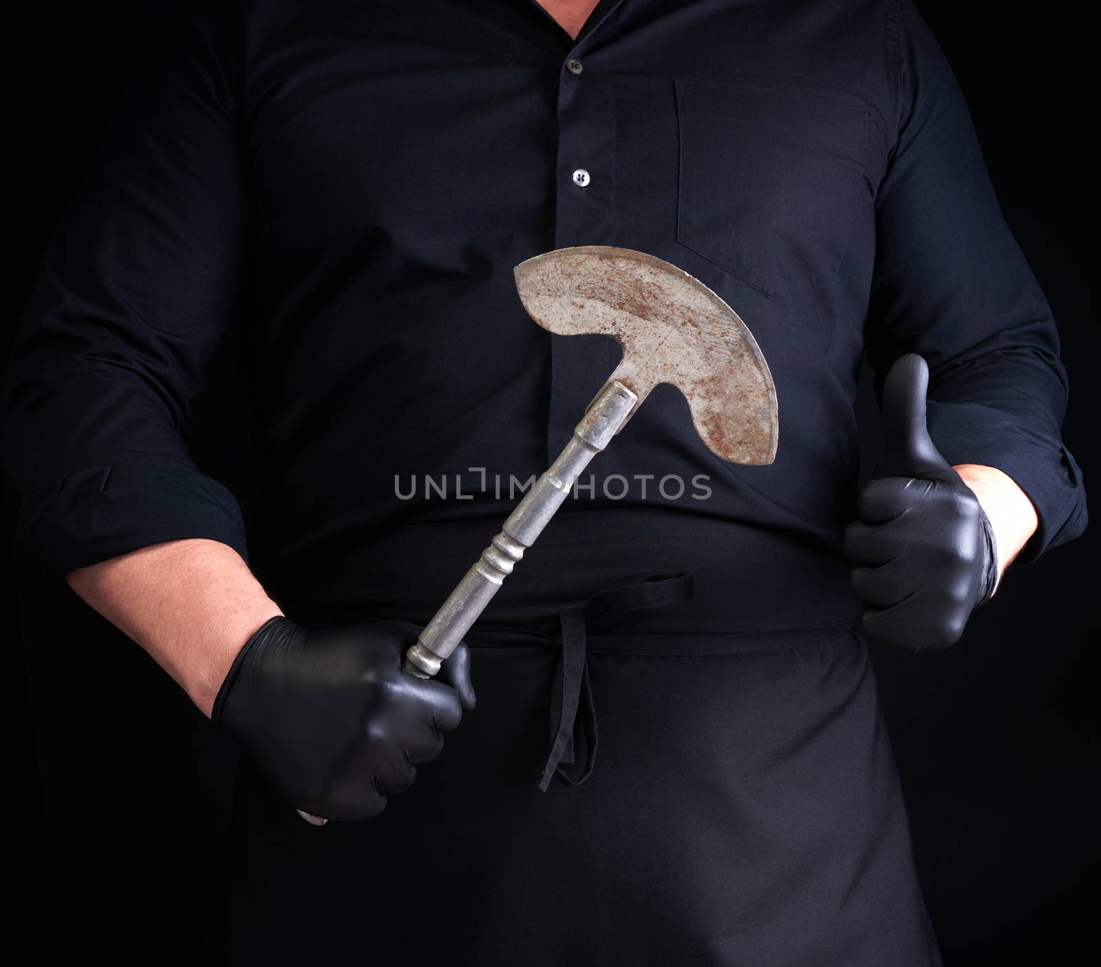 man in black clothes, latex gloves holds a vintage metal ax-knife for meat and vegetables, dark background
