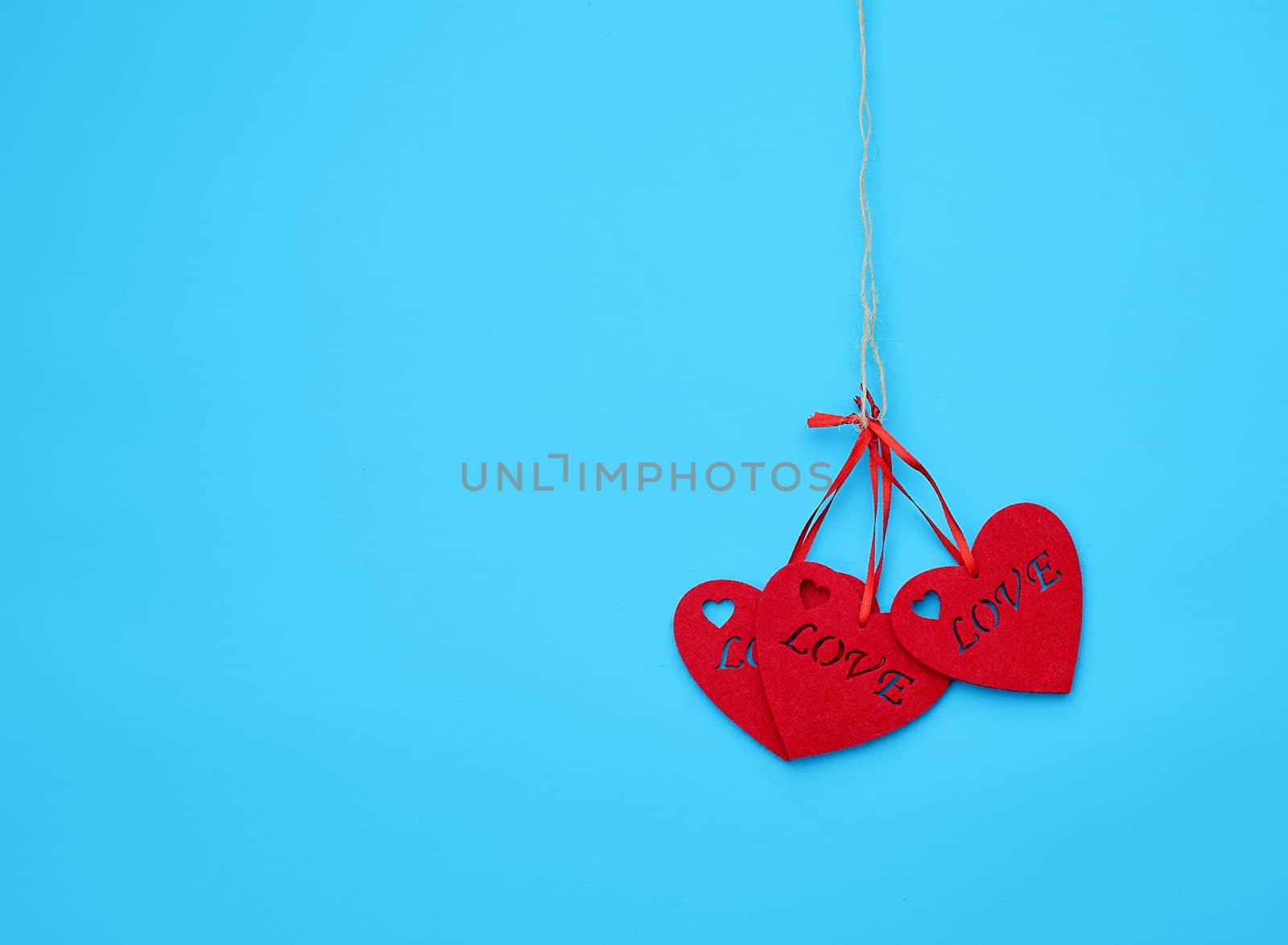 red felt hearts hanging on a brown rope, blue background. Holiday celebration concept. 