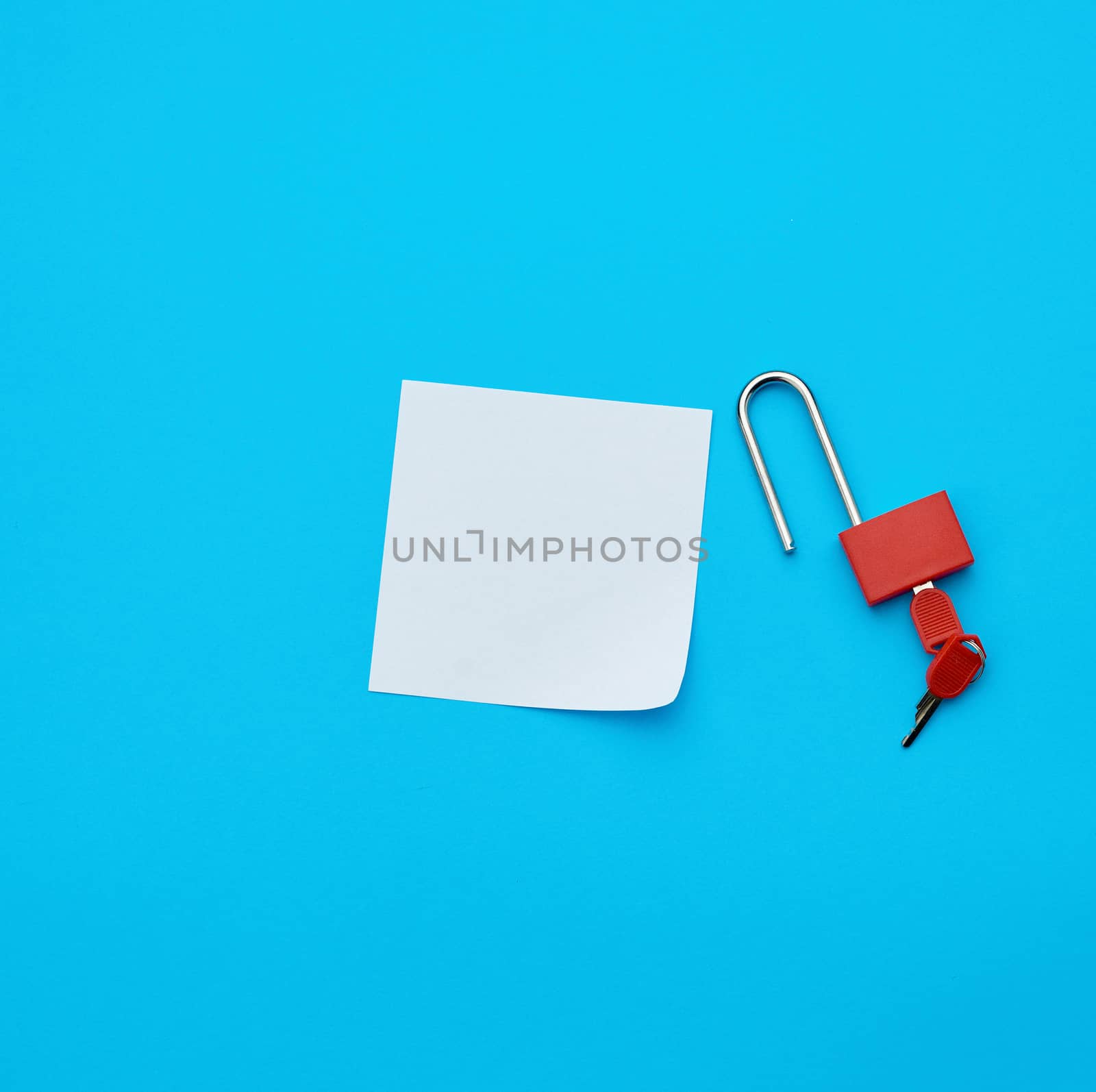 white paper and metal open padlock with keys on a blue background, copy space