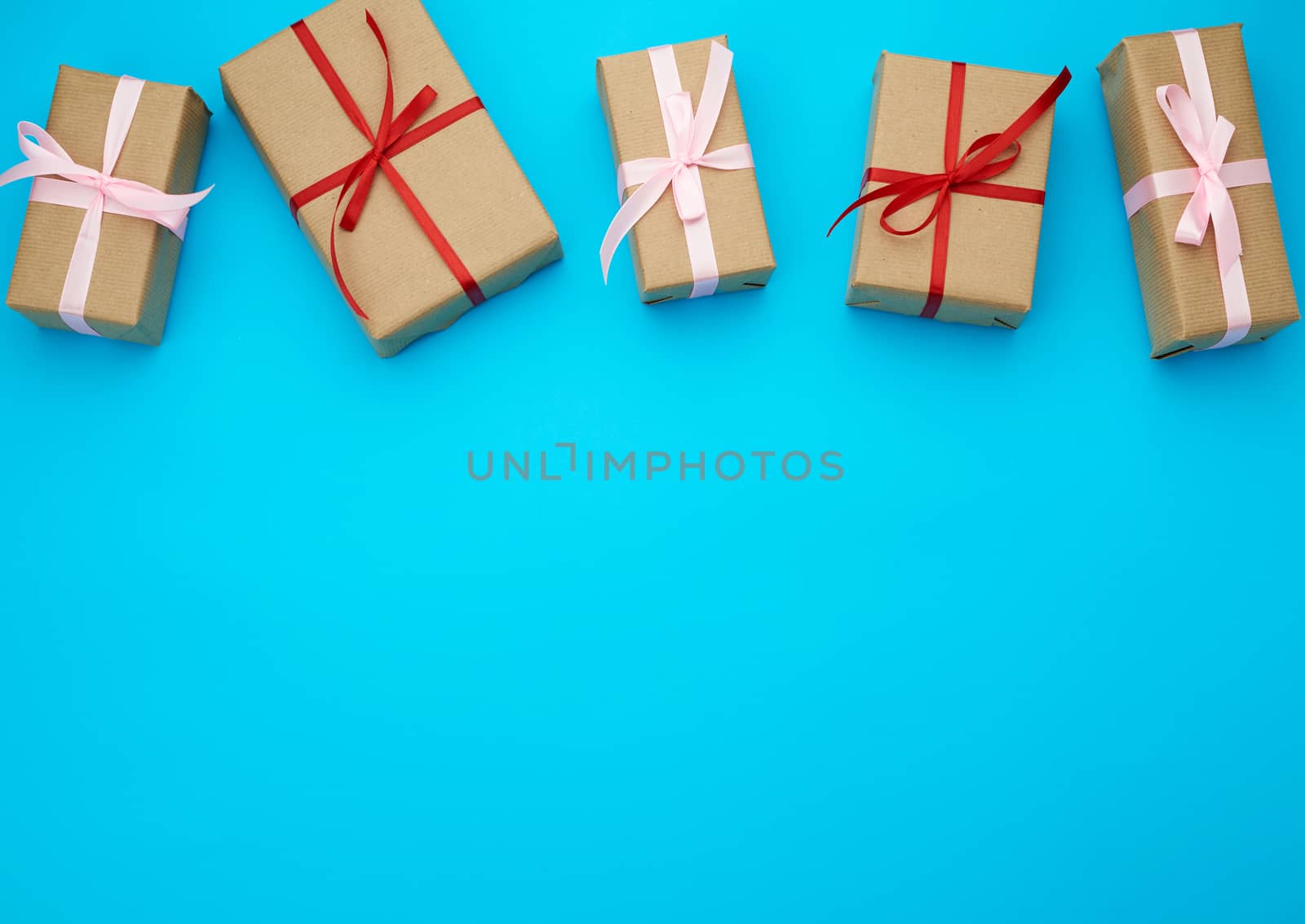 boxes wrapped in brown paper and tied with a red bow, gifts on a blue background, place for text