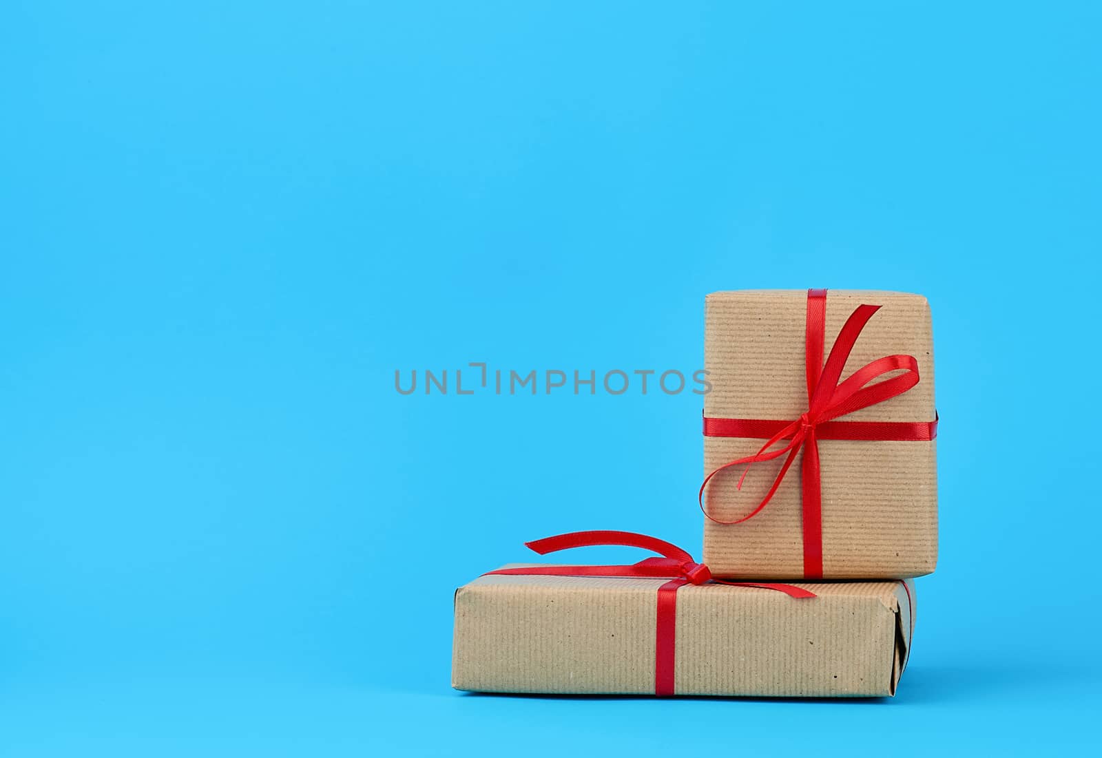 stack of boxes wrapped in brown paper and tied with a red bow, gifts on a blue background. Great design for any purposes. Holiday background. Valentine gift.