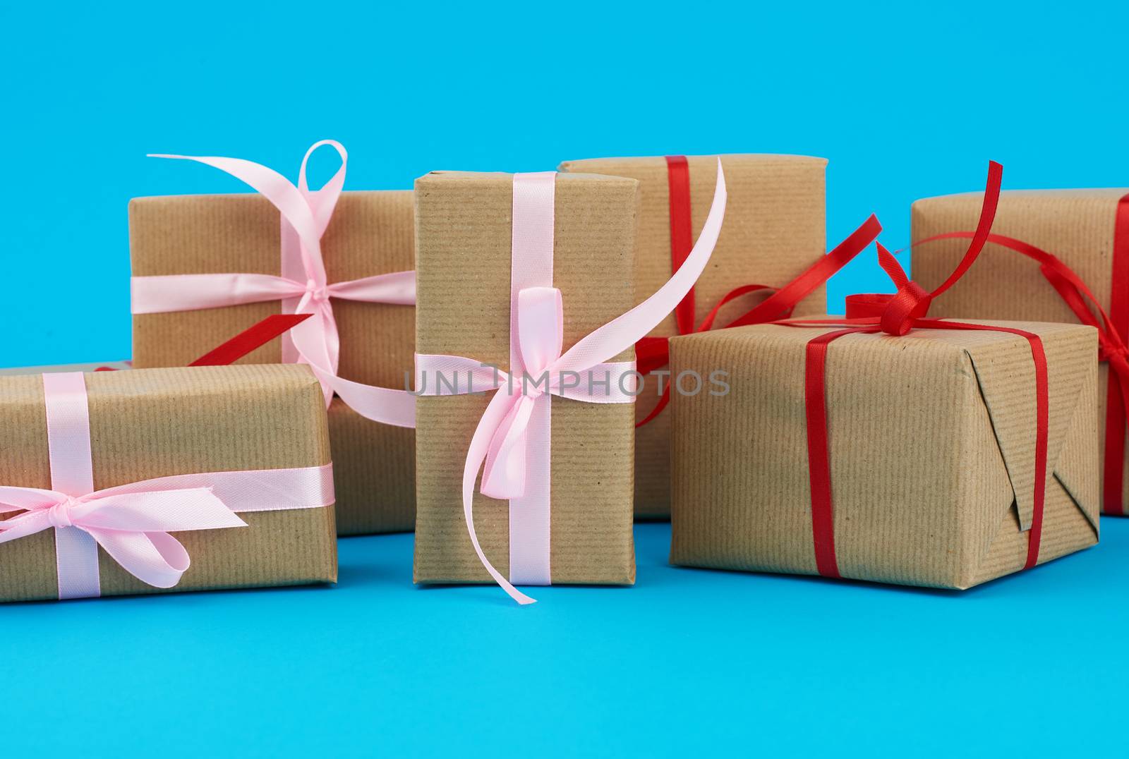 stack of boxes wrapped in brown paper and tied with a red bow, gifts on a blue background. Great design for any purposes. Holiday background. Valentine gift.