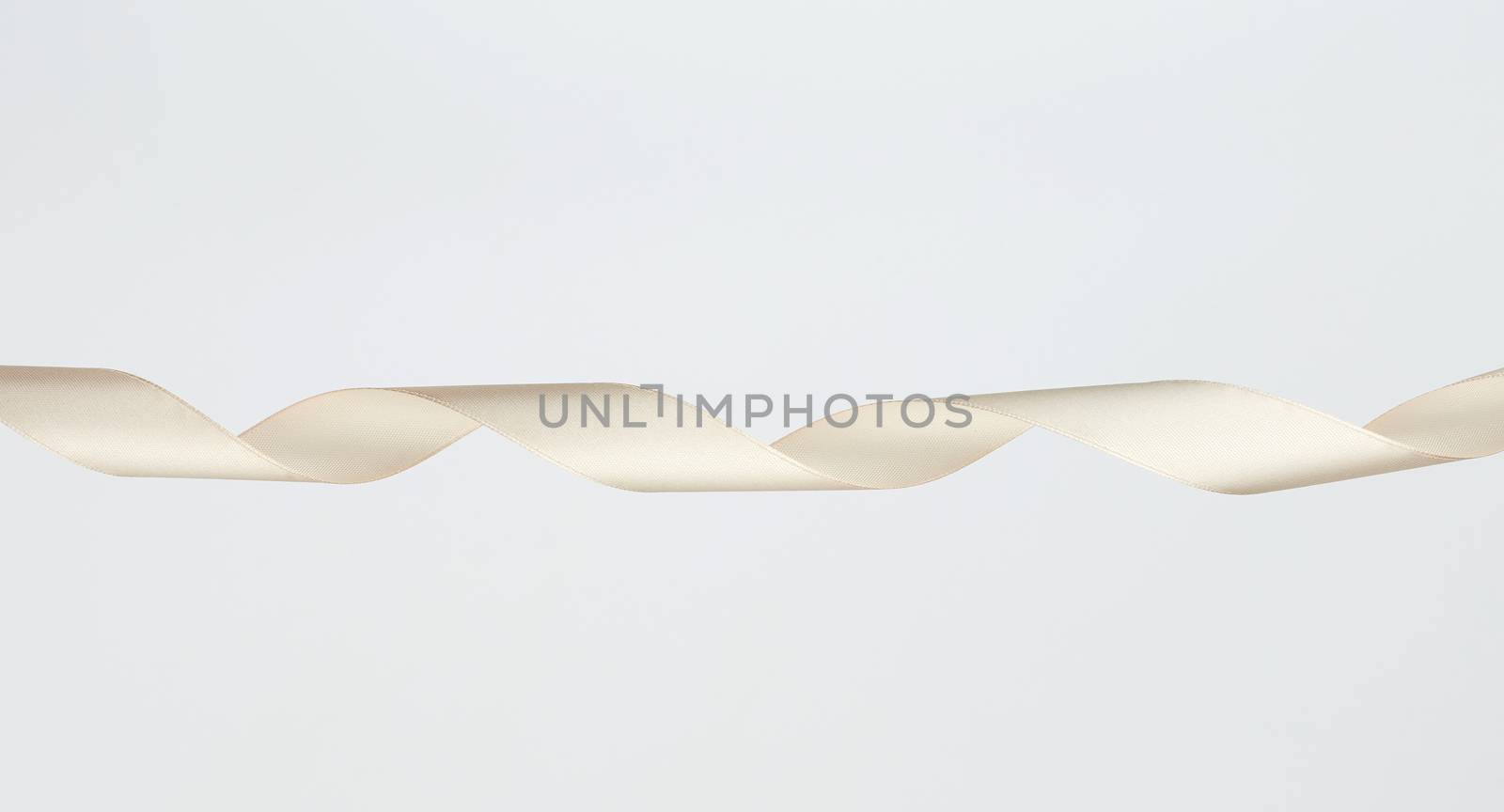 twisted beige silk decorative ribbon for packing gifts on a white background, close up