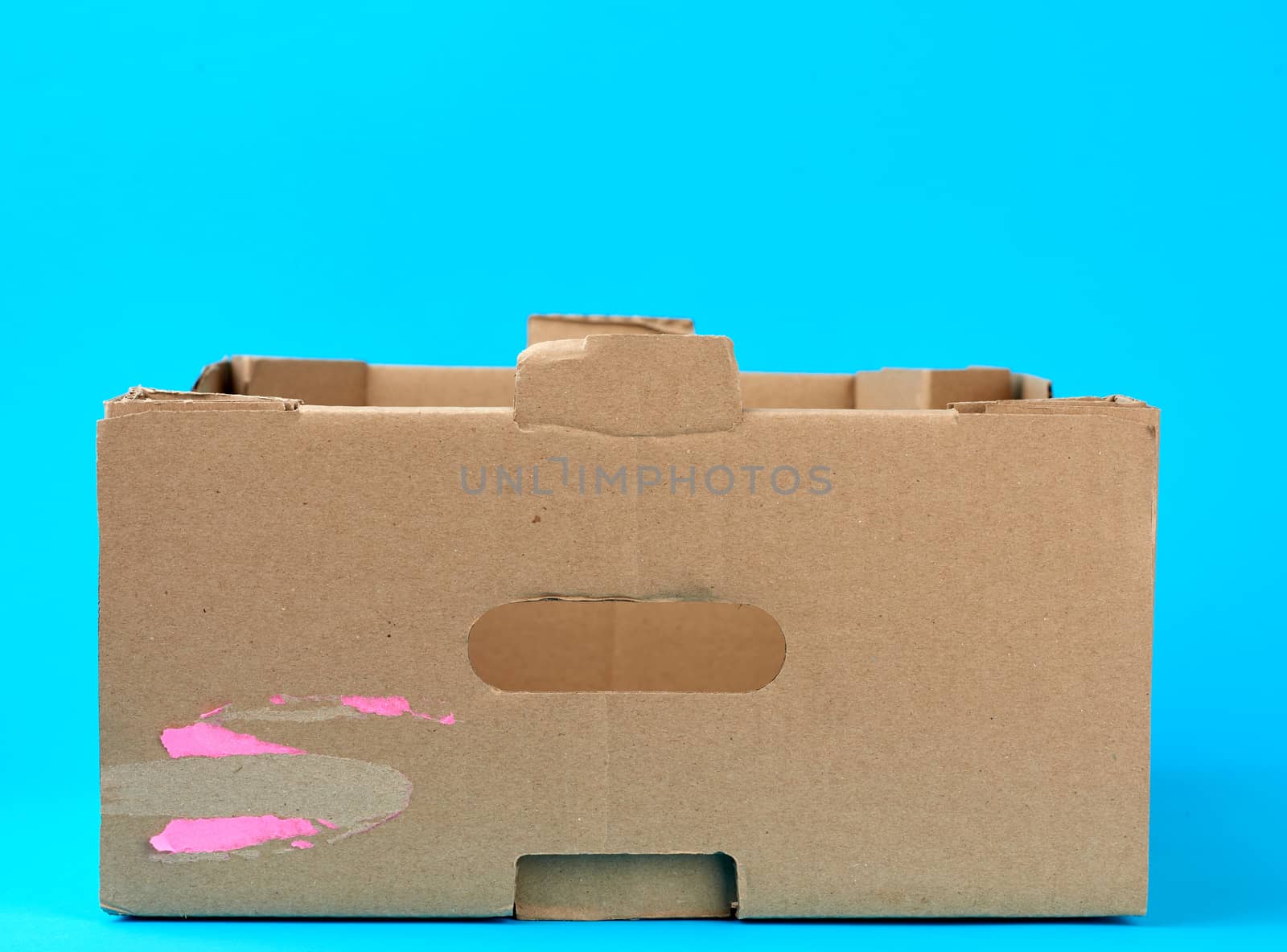 rectangular empty cardboard box of brown paper on a blue background, box without a lid for vegetables and fruits in with holes