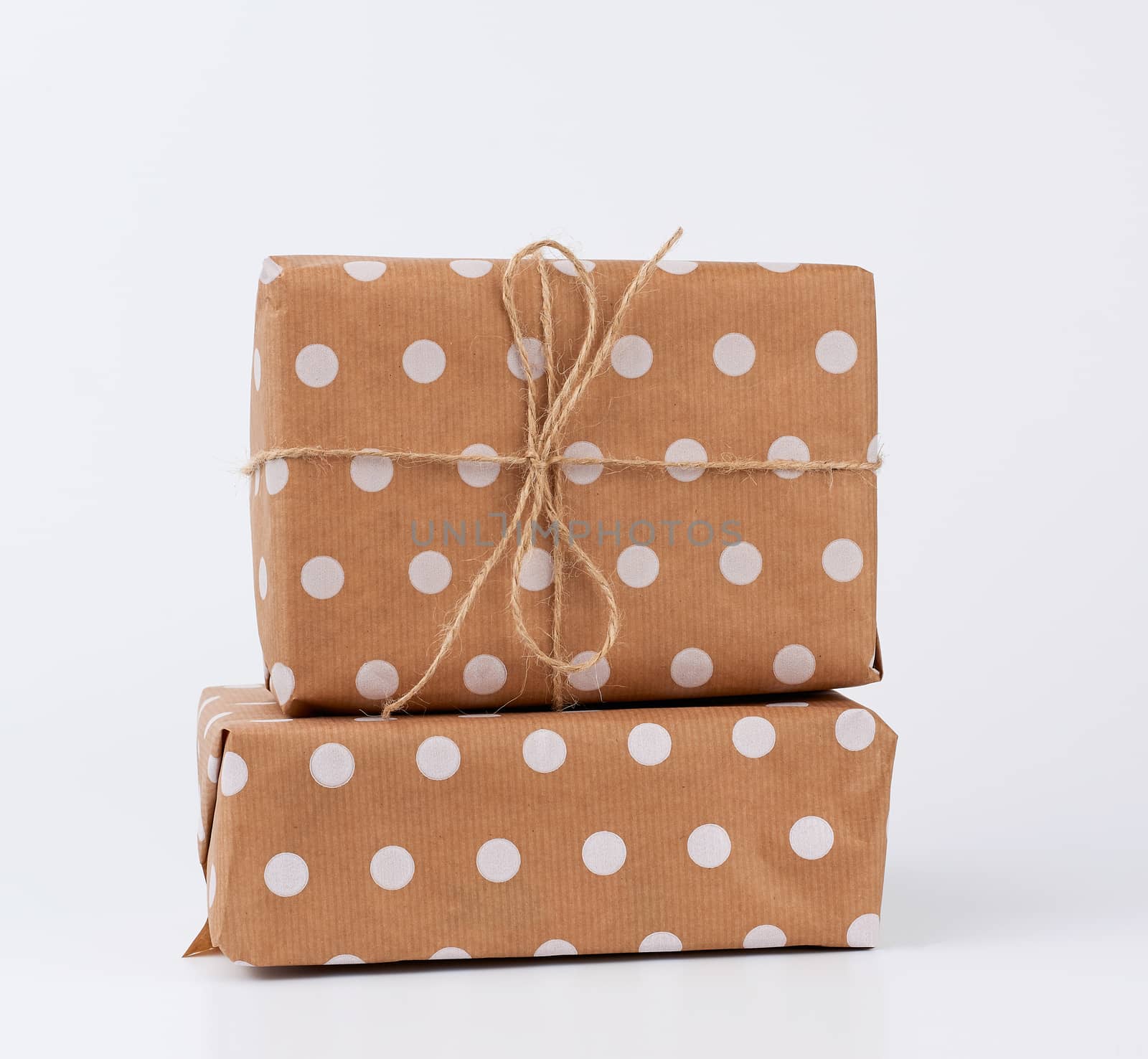 stack of gifts in boxes wrapped in brown kraft paper and tied with rope on a white background. Festive concept, copy space