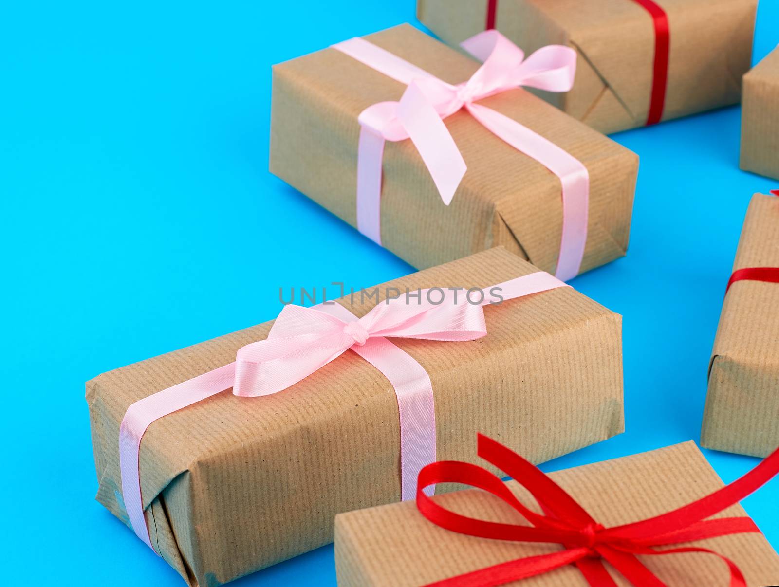 boxes wrapped in brown paper and tied with a silk ribbon, gifts on a blue background, top view. Festive concept