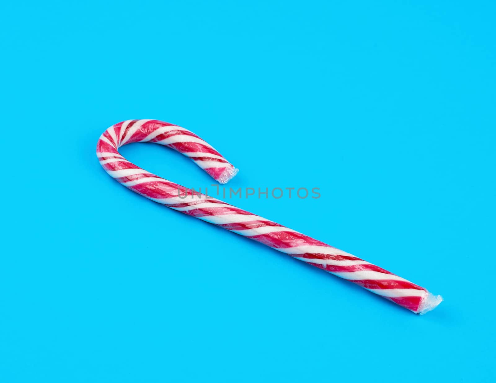 red-white candy stick in transparent cellophane on a blue background