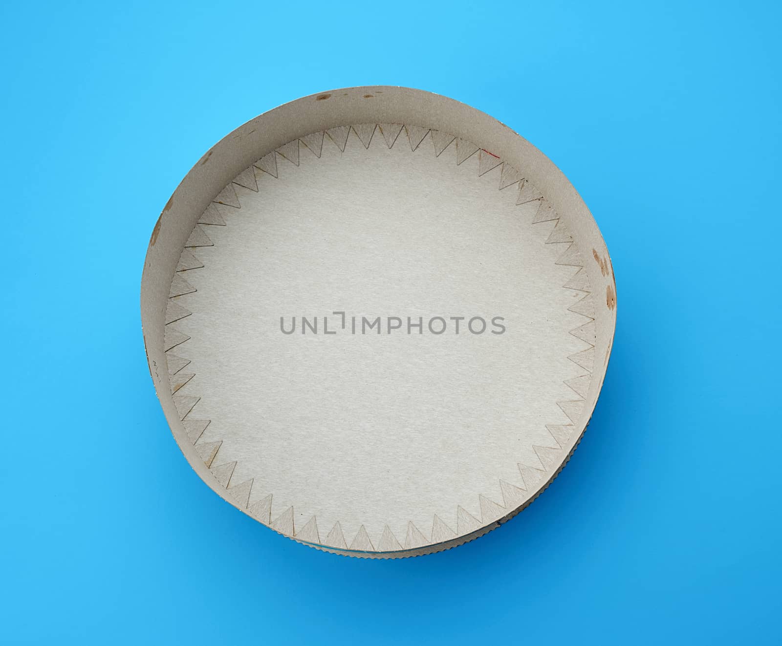empty cardboard round cover for packing a cake on a blue background, top view