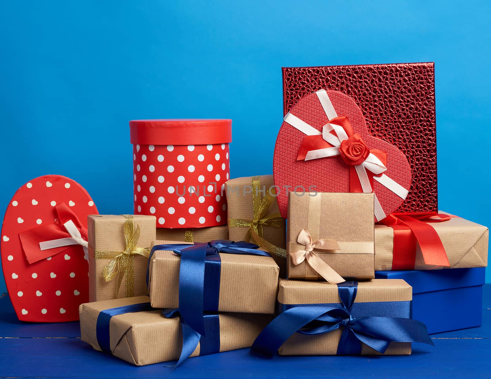 gifts in boxes wrapped in brown kraft paper and tied with silk ribbons on a blue background, festive backdrop for birthday, Christmas