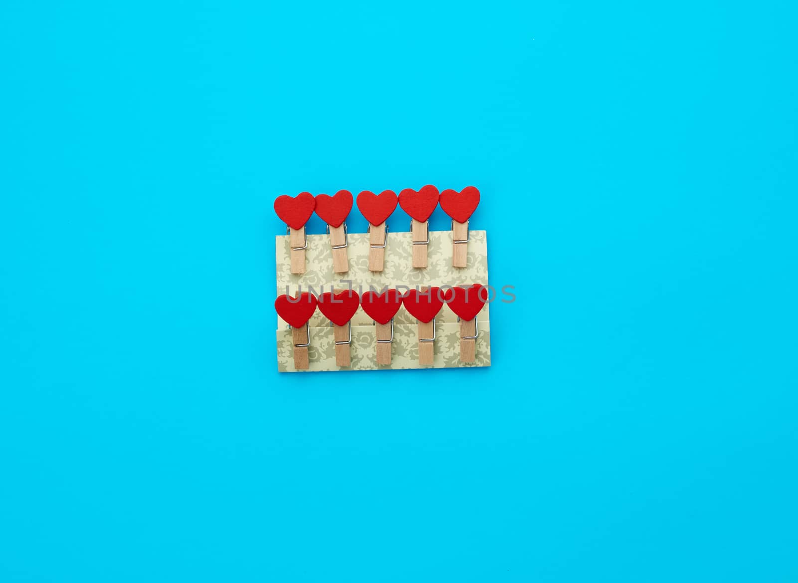 wooden decorative clothespins on a blue background with red hearts, top view