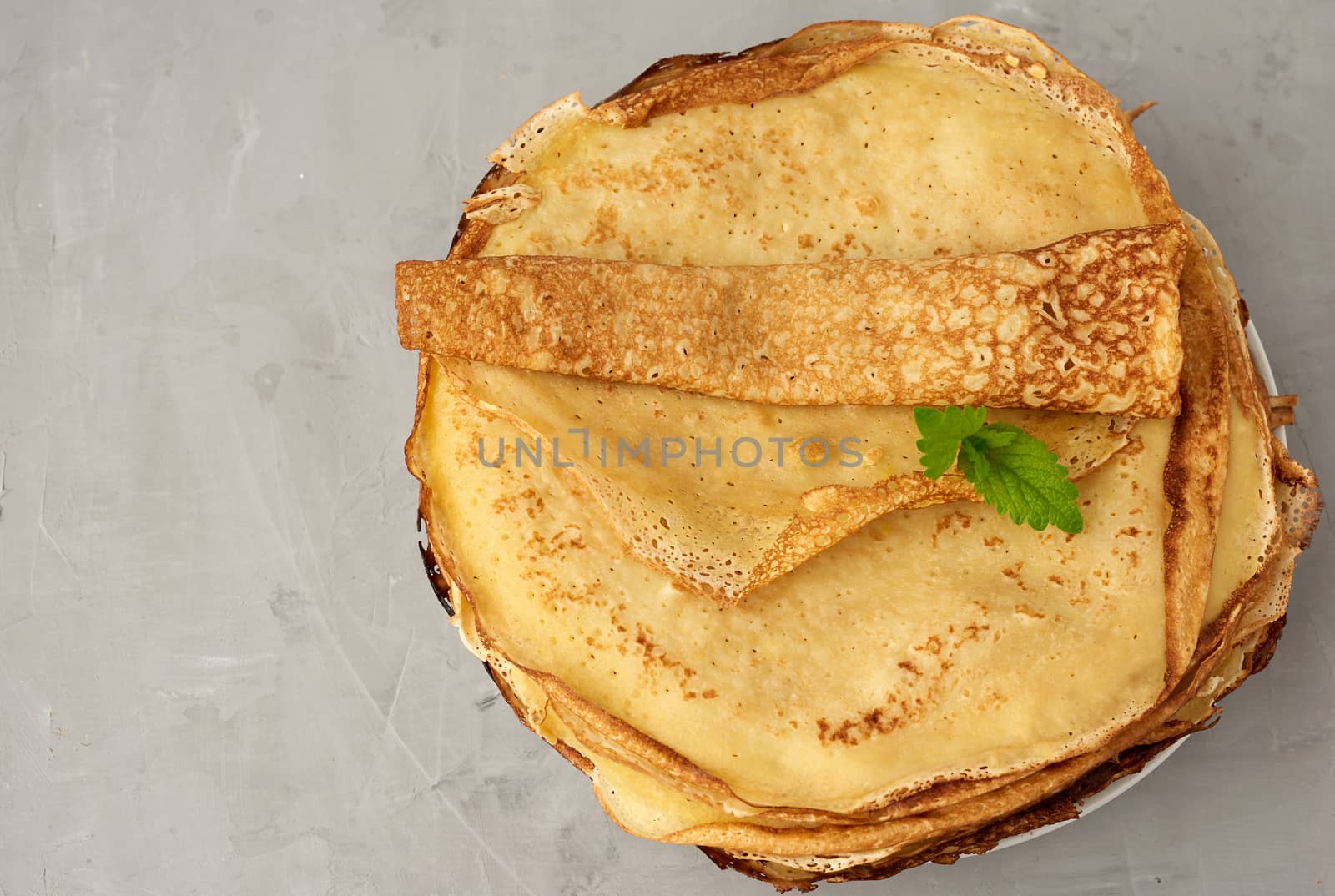 stack of fried round pancakes on a plate, gray background, top view, copy space