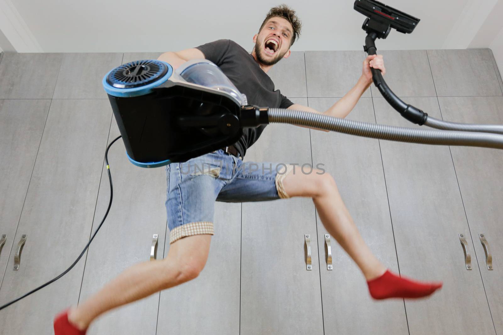 House cleaning. Jumping man with vacuum cleaner. Сleaned apartment