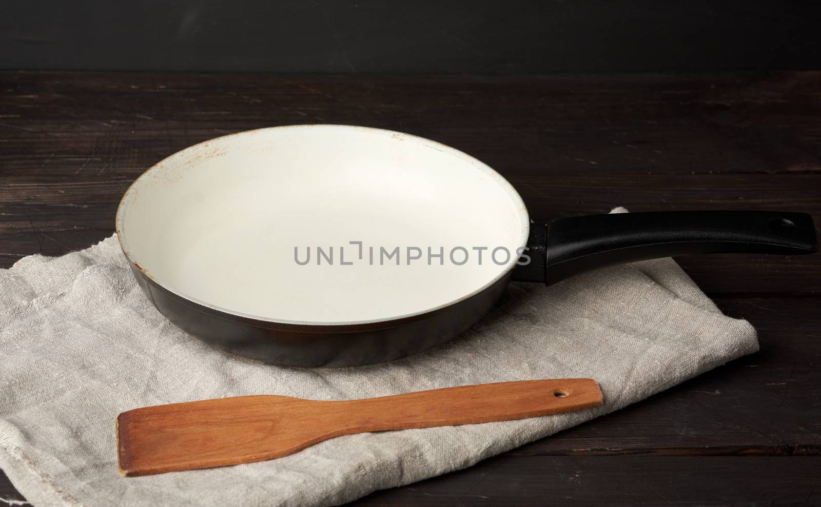 round iron empty pan and wooden spatula on the table, kitchen utensils