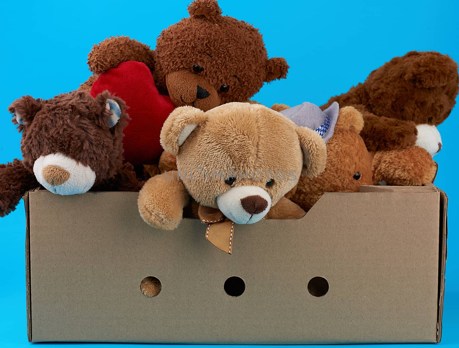 brown cardboard box with various teddy bears, blue background, concept of assistance and volunteering
