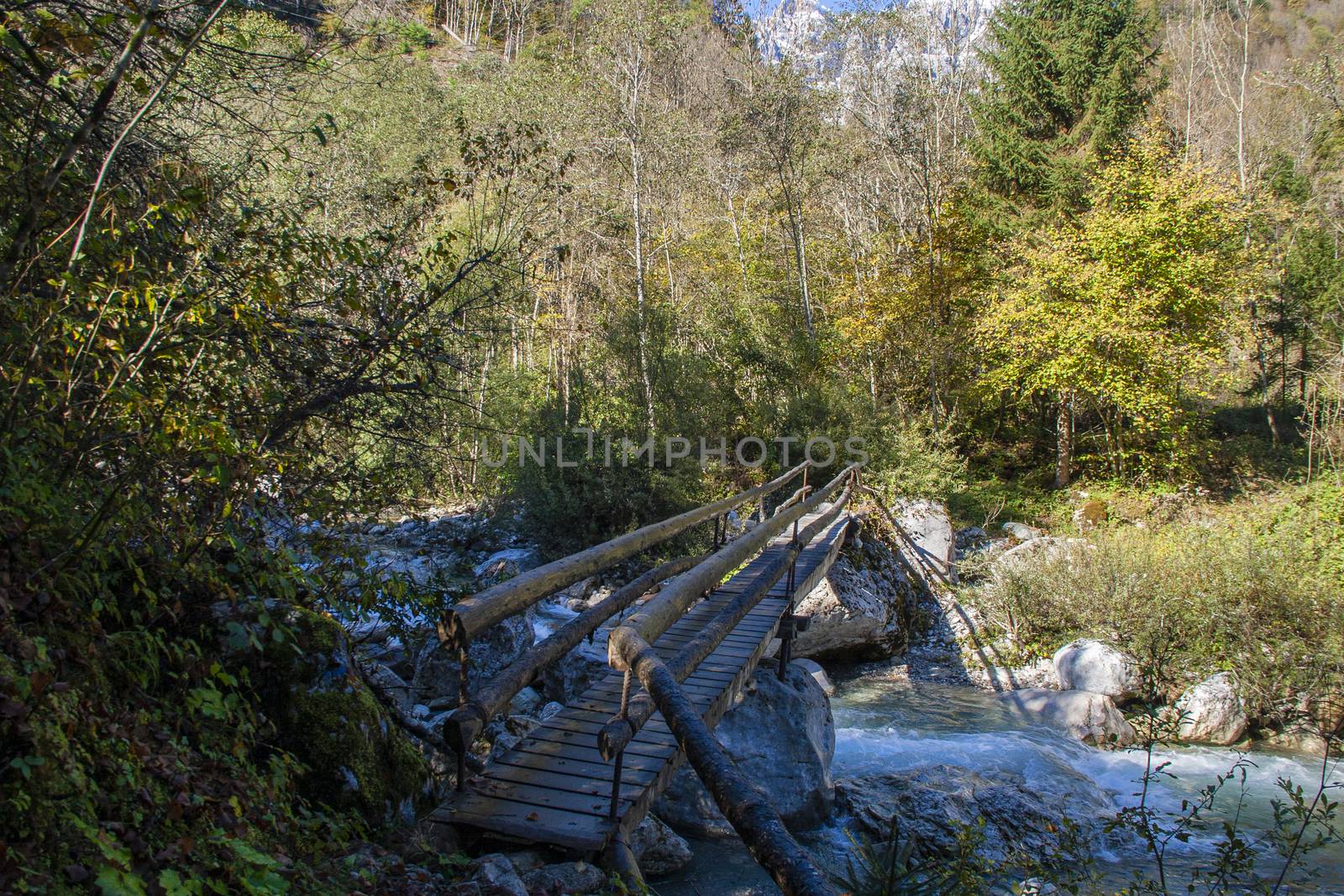 Bridge over the mountain stream in the middle of dolomites mountains in Italy