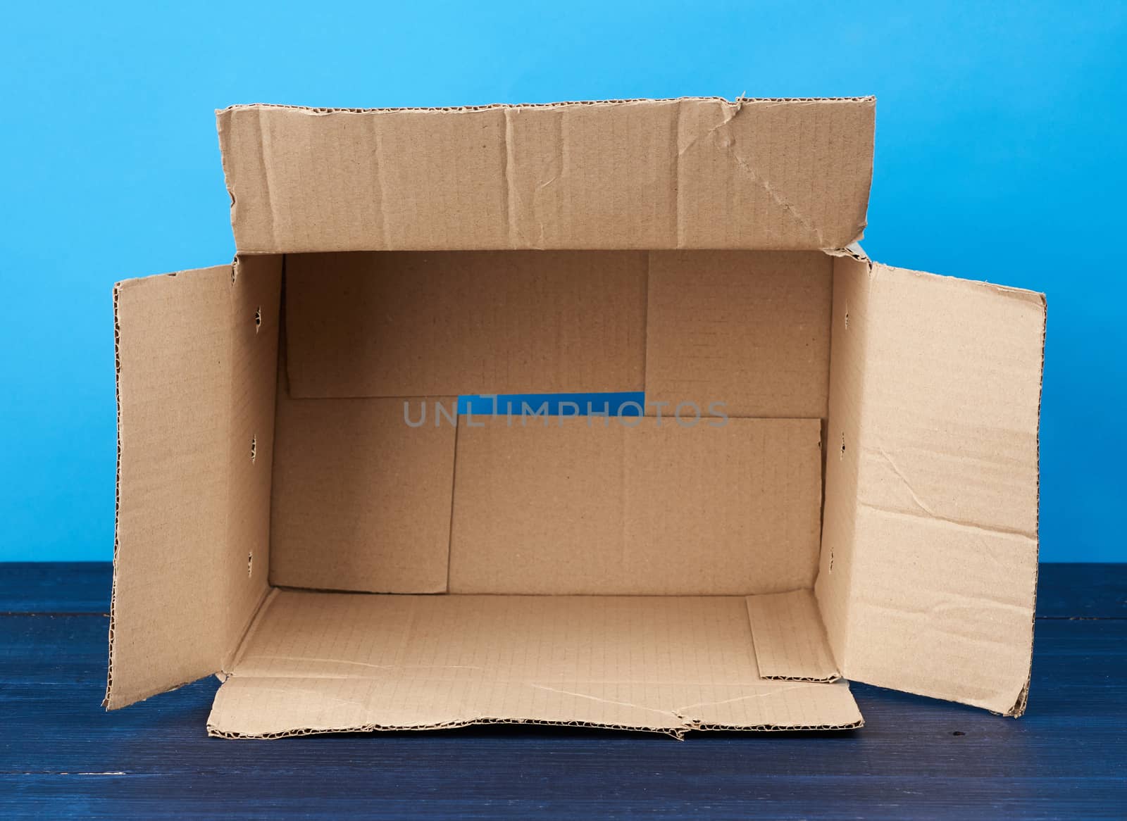 open empty brown rectangular cardboard box for transporting goods on blue wooden background