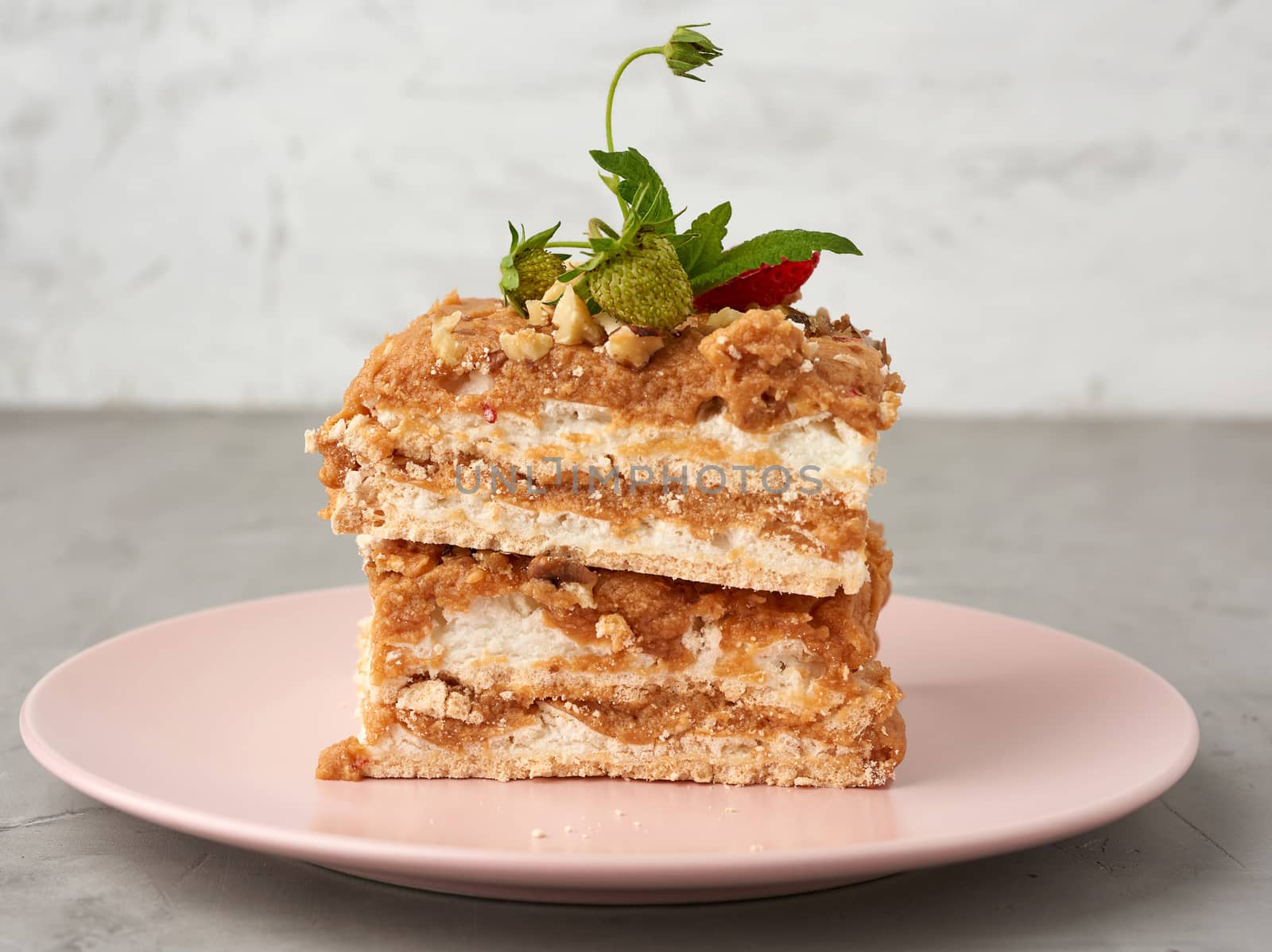 square pieces of meringue cake with cream on a pink plate , close up