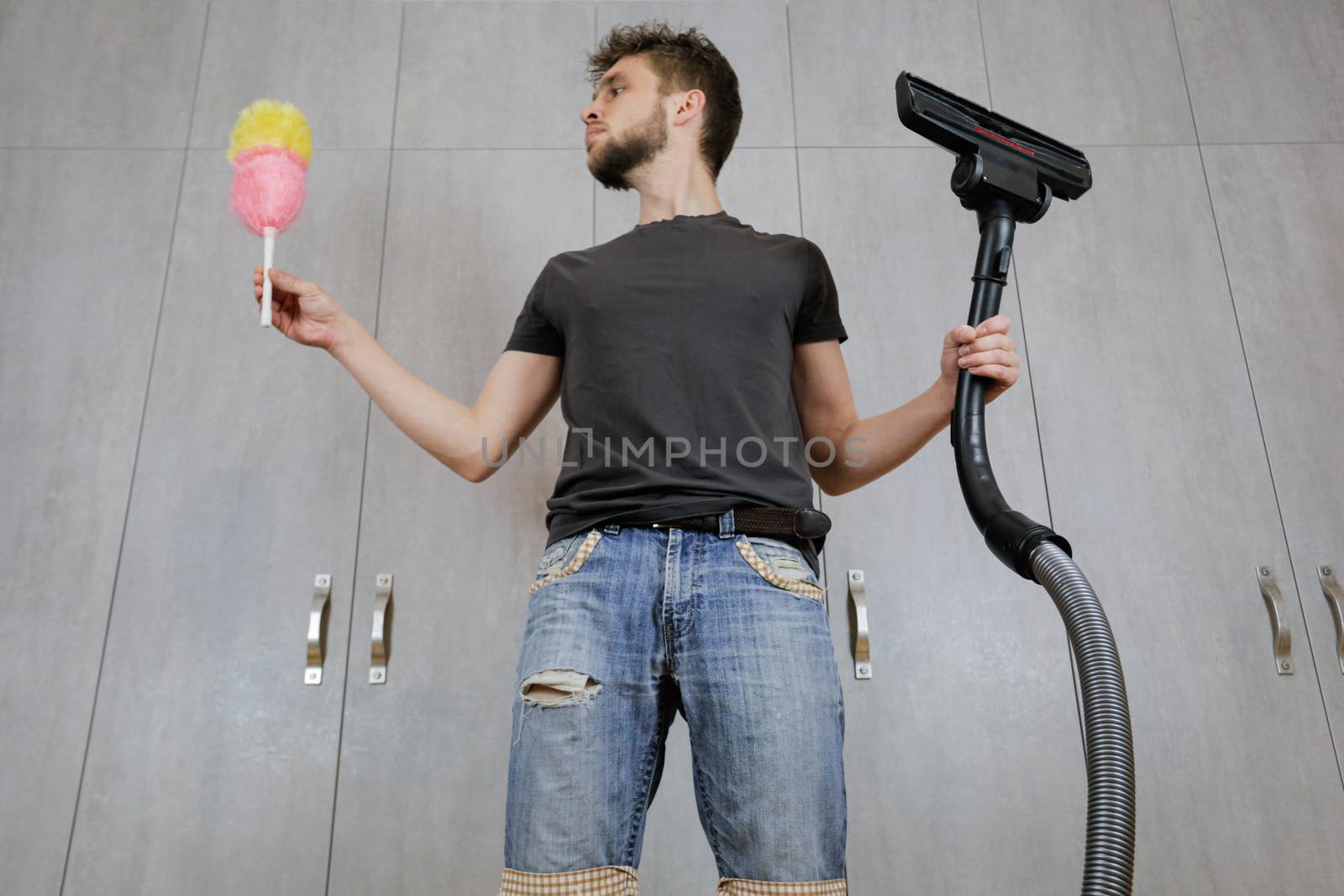 A man with a dust brush and a vacuum cleaner. House cleaning.