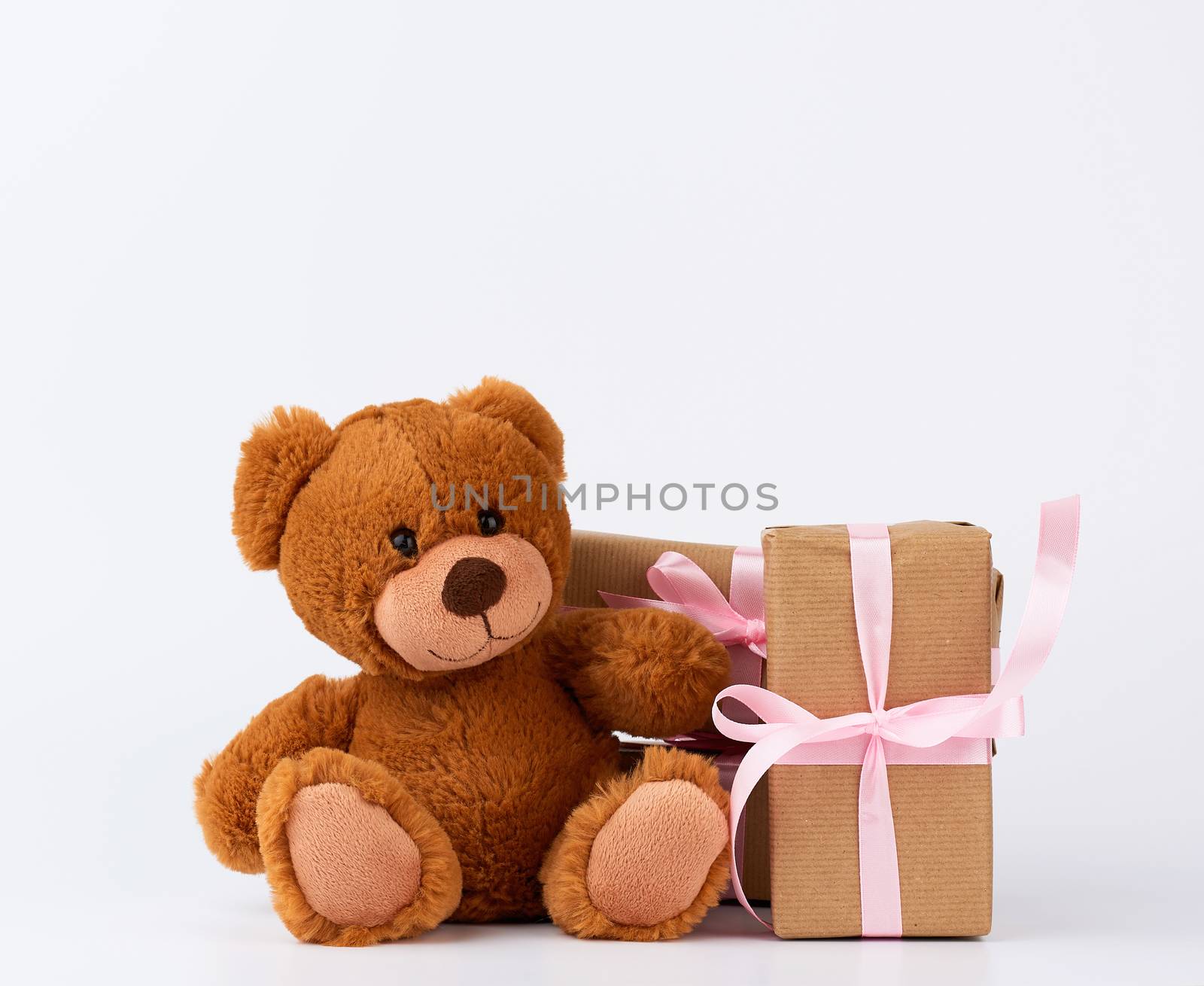 brown teddy bear, stack of gifts in boxes wrapped in brown paper, tied with silk ribbon, happy birthday and valentines da