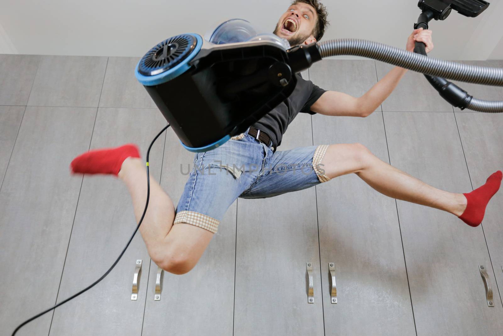 House cleaning. Jumping man with vacuum cleaner. Сleaned apartment