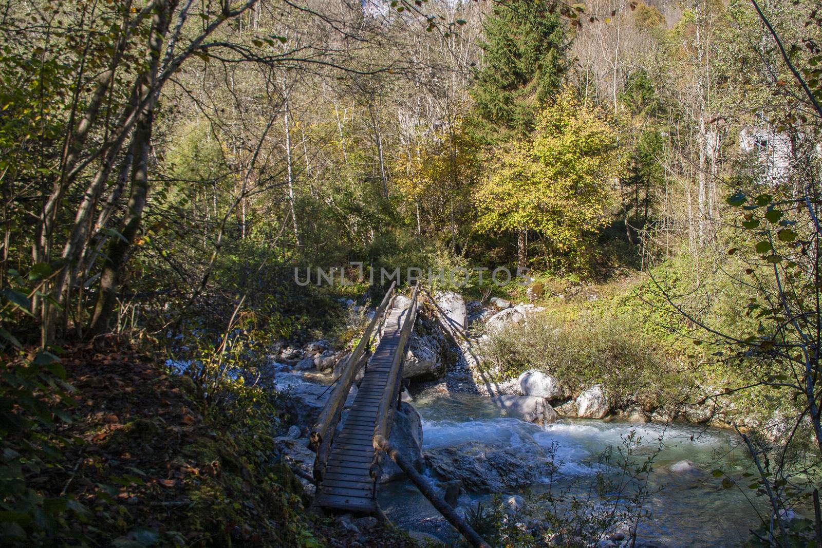 Bridge over the mountain stream in the middle of dolomites mountains in Italy