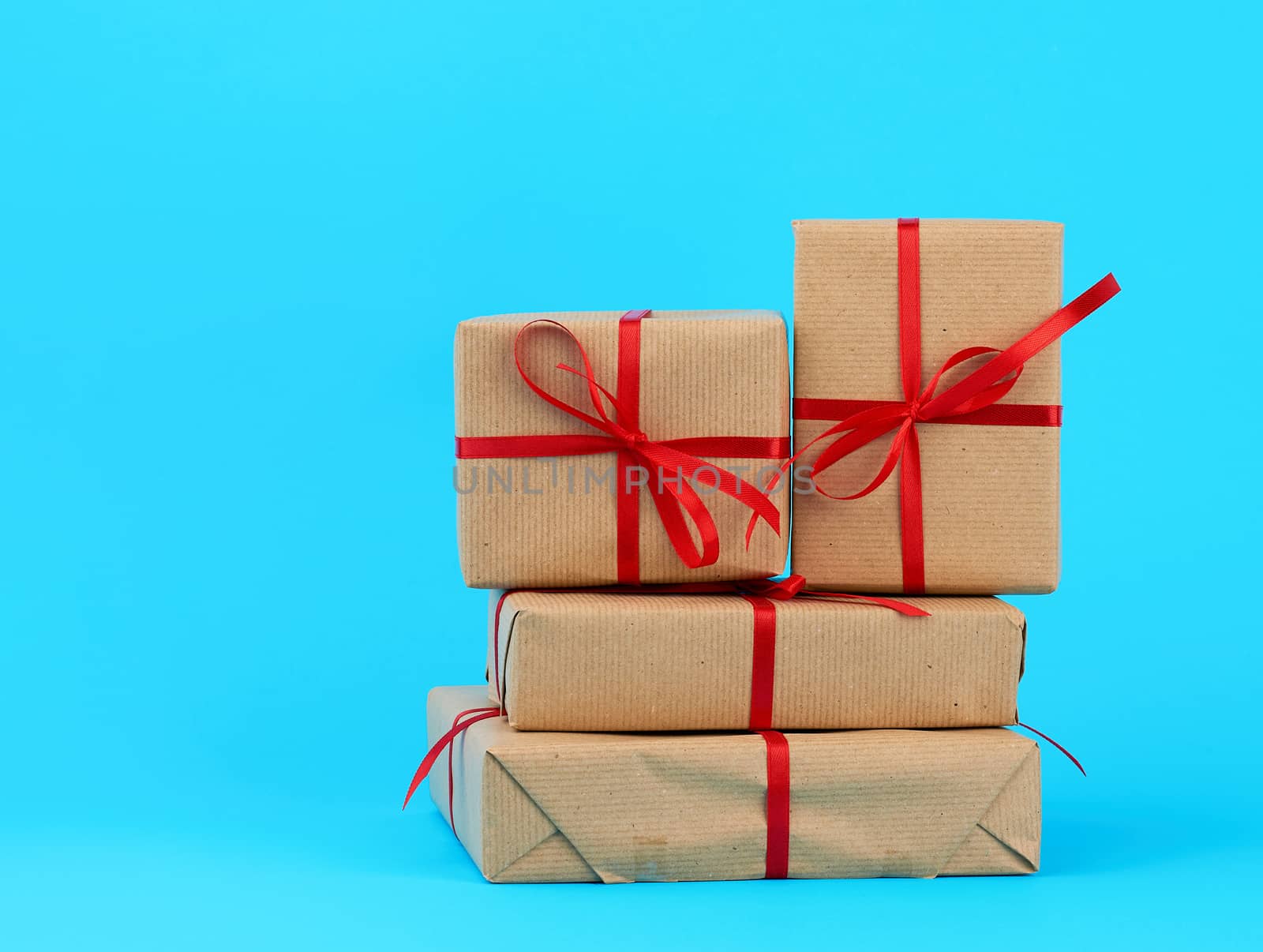 stack of boxes wrapped in brown paper and tied with a red bow, gifts on a blue background. Great design for any purposes. Holiday background. Valentine gift.